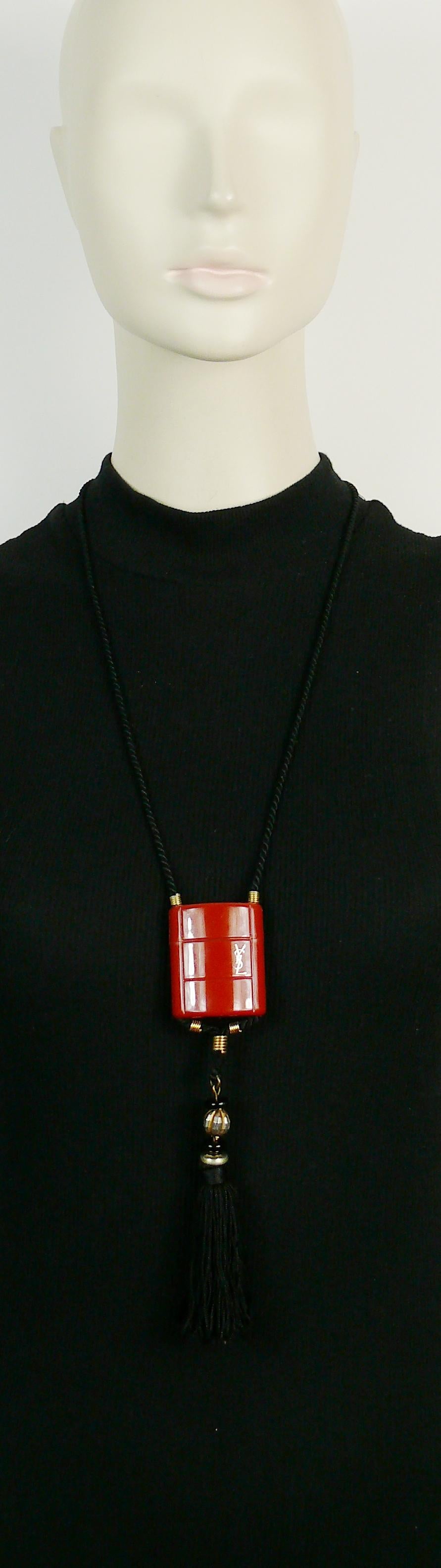 YVES SAINT LAURENT vintage OPIUM inro pendant necklace.

This necklace consists of a black cord, a burnt orange plastic container, a silk tassel adorned with black and gold tone beads.

Plastic container opens to insert a miniature bottle (empty