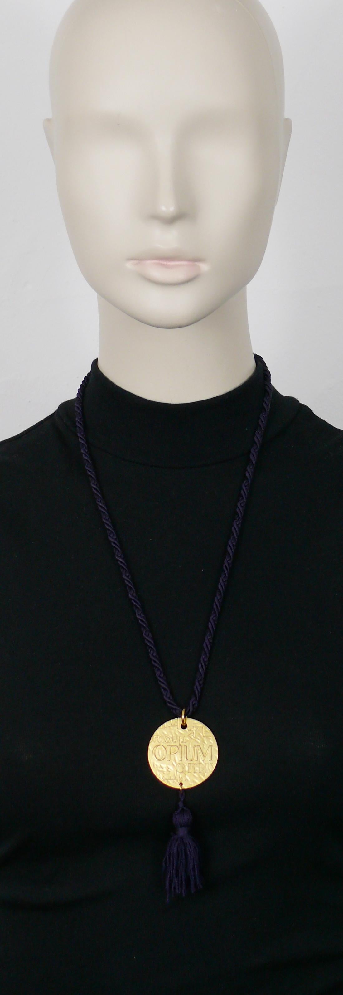 YVES SAINT LAURENT Vintage-Halskette mit Medaillon-Anhänger aus OPIUM. Lila Passepartout-Seil und Quaste.

Gekennzeichnet mit YSL Made in France.

Ungefähre Maße: getragene Länge (einschließlich Quaste) ca. 37,5 cm / Durchmesser des Anhängers ca.