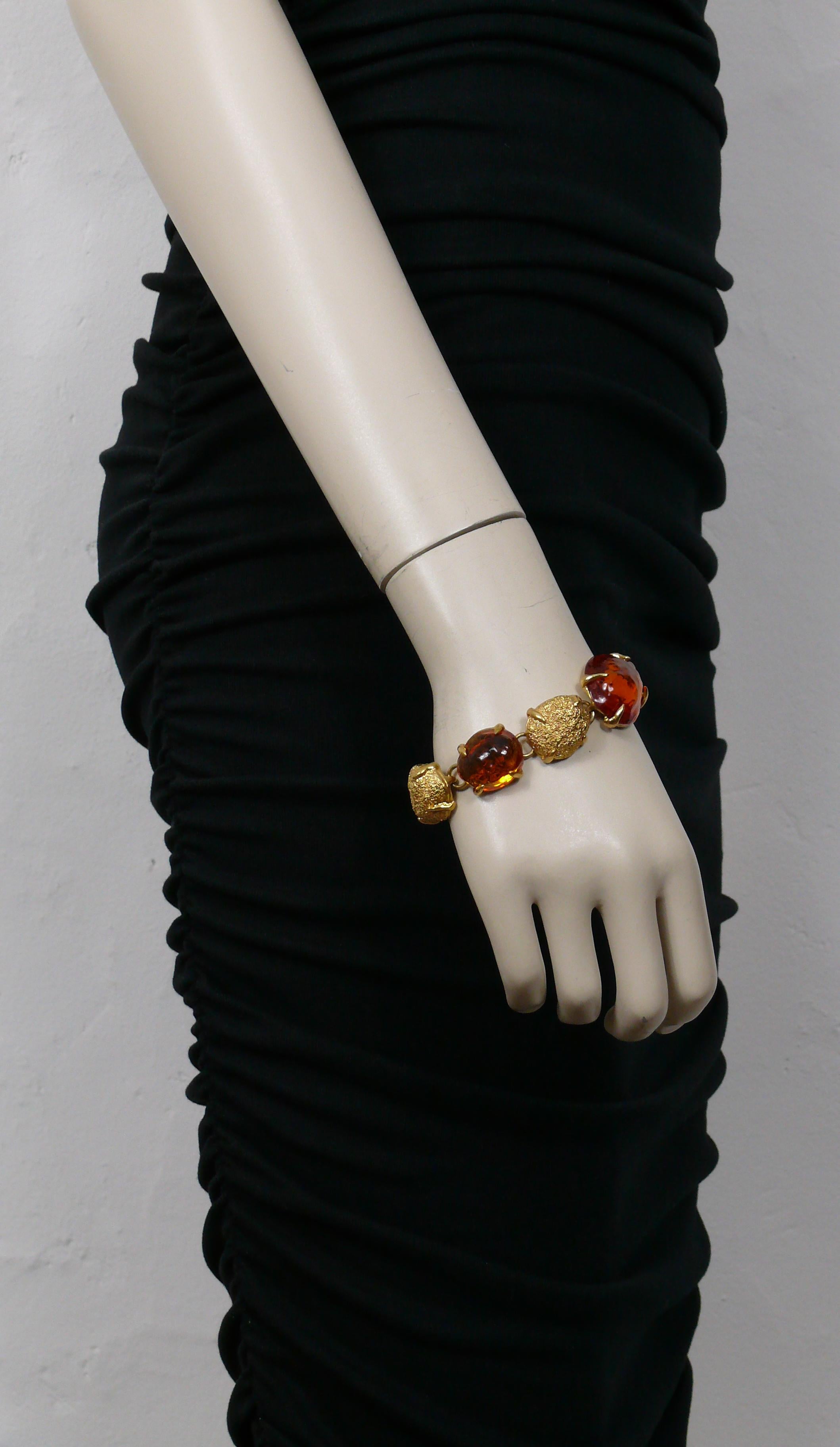 Bracelet vintage Yves SAINT LAURENT by ROBERT GOOSSENS composé de pépites ovales texturées en ton or et agrémentées de cabochons de résine orange de forme irrégulière.

Embossé YVES SAINT LAURENT Made in France.

Mesures indicatives : longueur