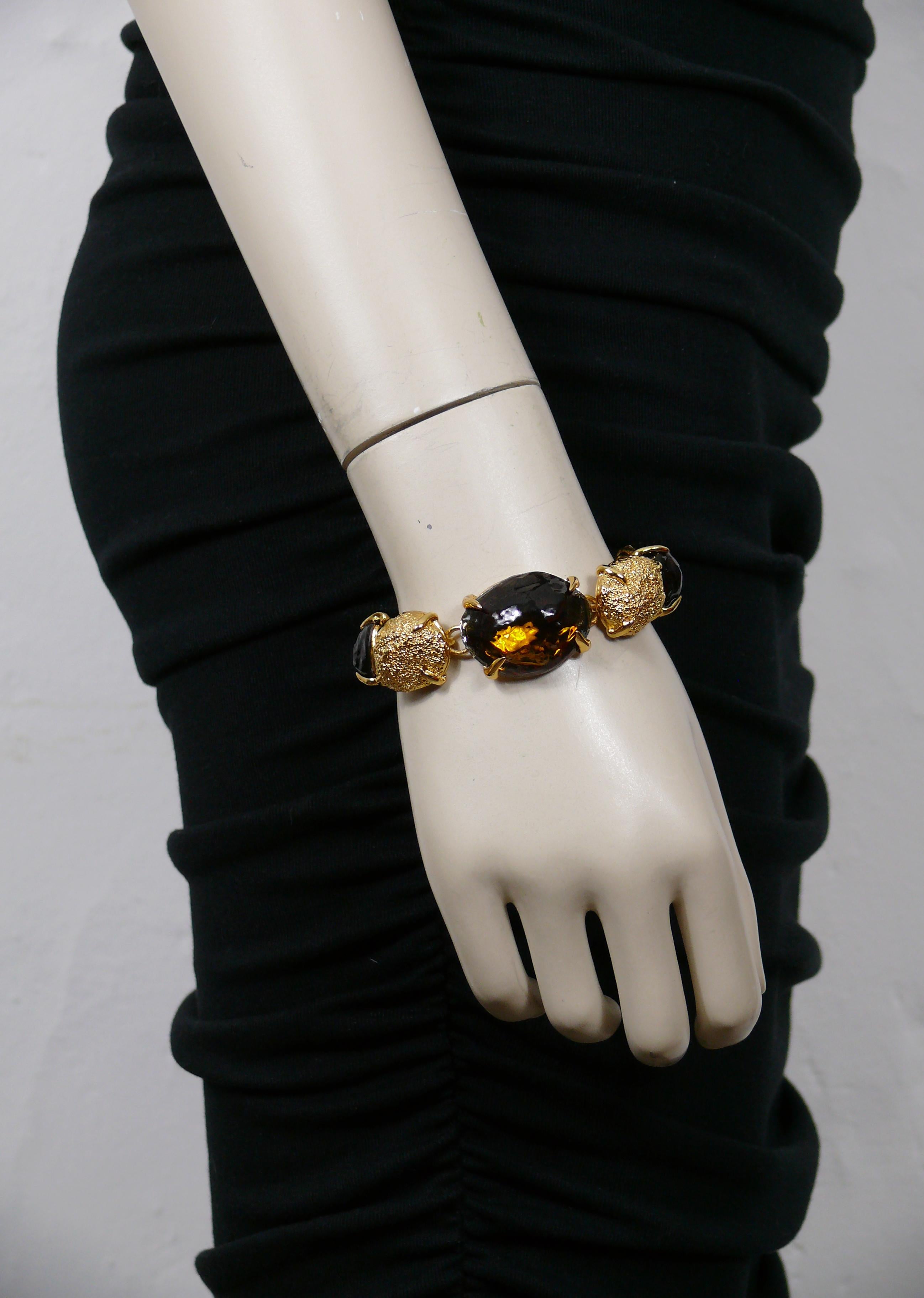 YVES SAINT LAURENT vintage gold tone oval nugget link bracelet featuring irregular shaped resin cabochons in smoky topaz colour.

Toggle and loop closure.
Adjustable length.

Embossed with YVES SAINT LAURENT cursive signature on the hearts.
Made in