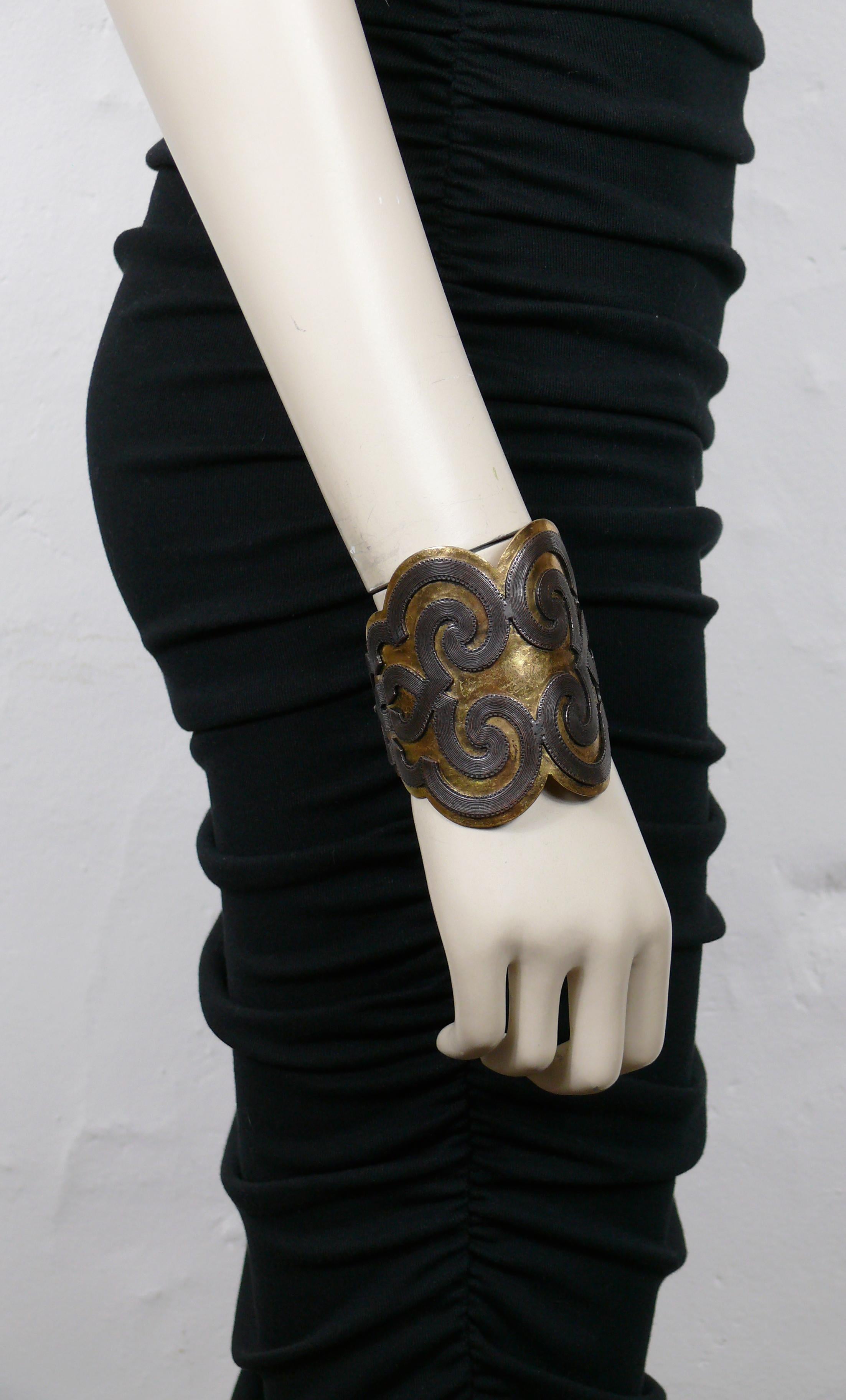 YVES SAINT LAURENT vintage hammered gold tone cuff bracelet featuring a bronze tone arabesque design onlaid.

Embossed YSL.

Indicative measurements : inner circumference approx. 18.85 cm (7.42 inches) / max. width approx. 7.8 cm (3.07 inches) /