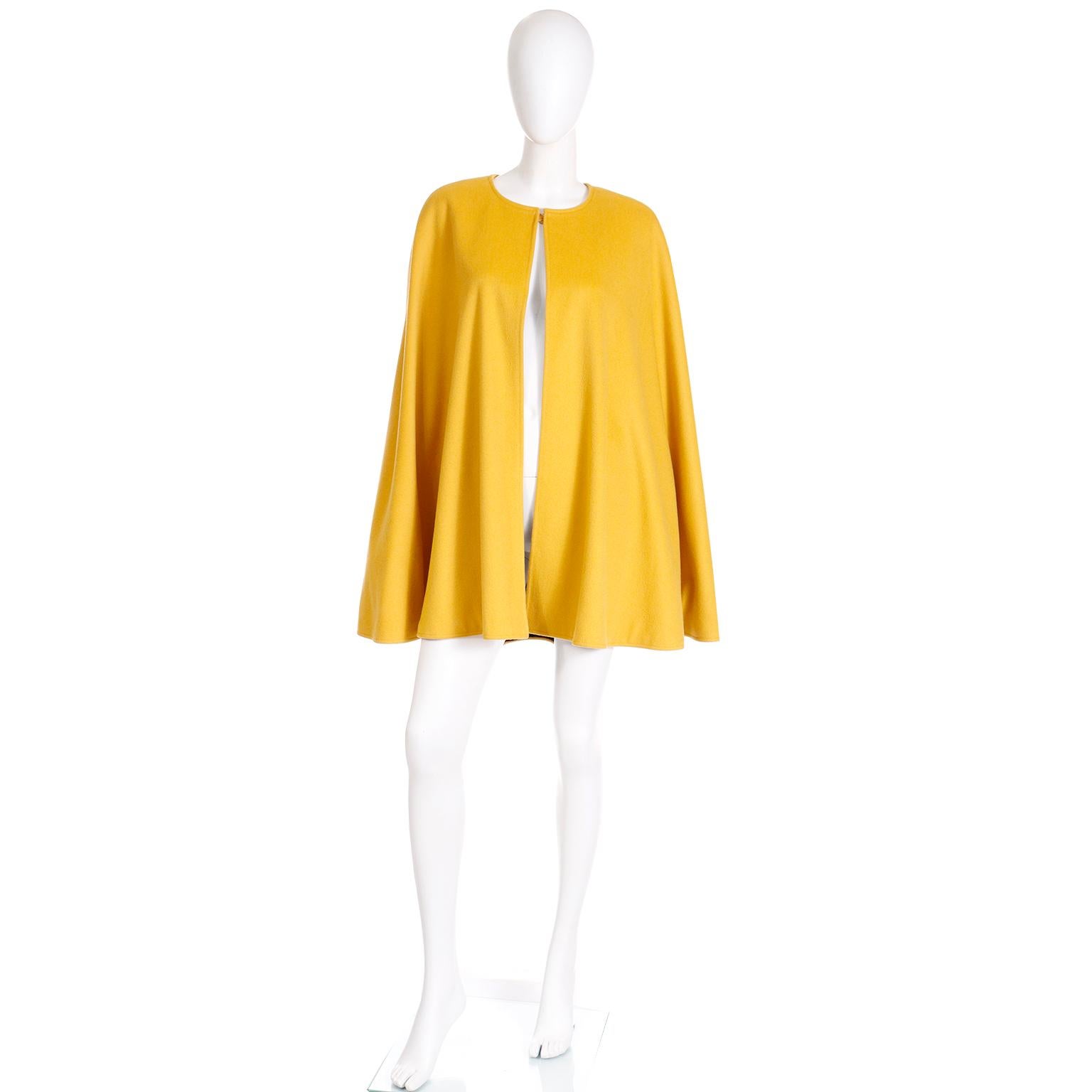 This is such a versatile Yves Saint Laurent vintage cape from the 1980s in a dandelion yellow wool with black lining. This collarless cape hits mid-thigh, and closes with a hidden mustard yellow button closure at the neck. 

Yves Saint Laurent