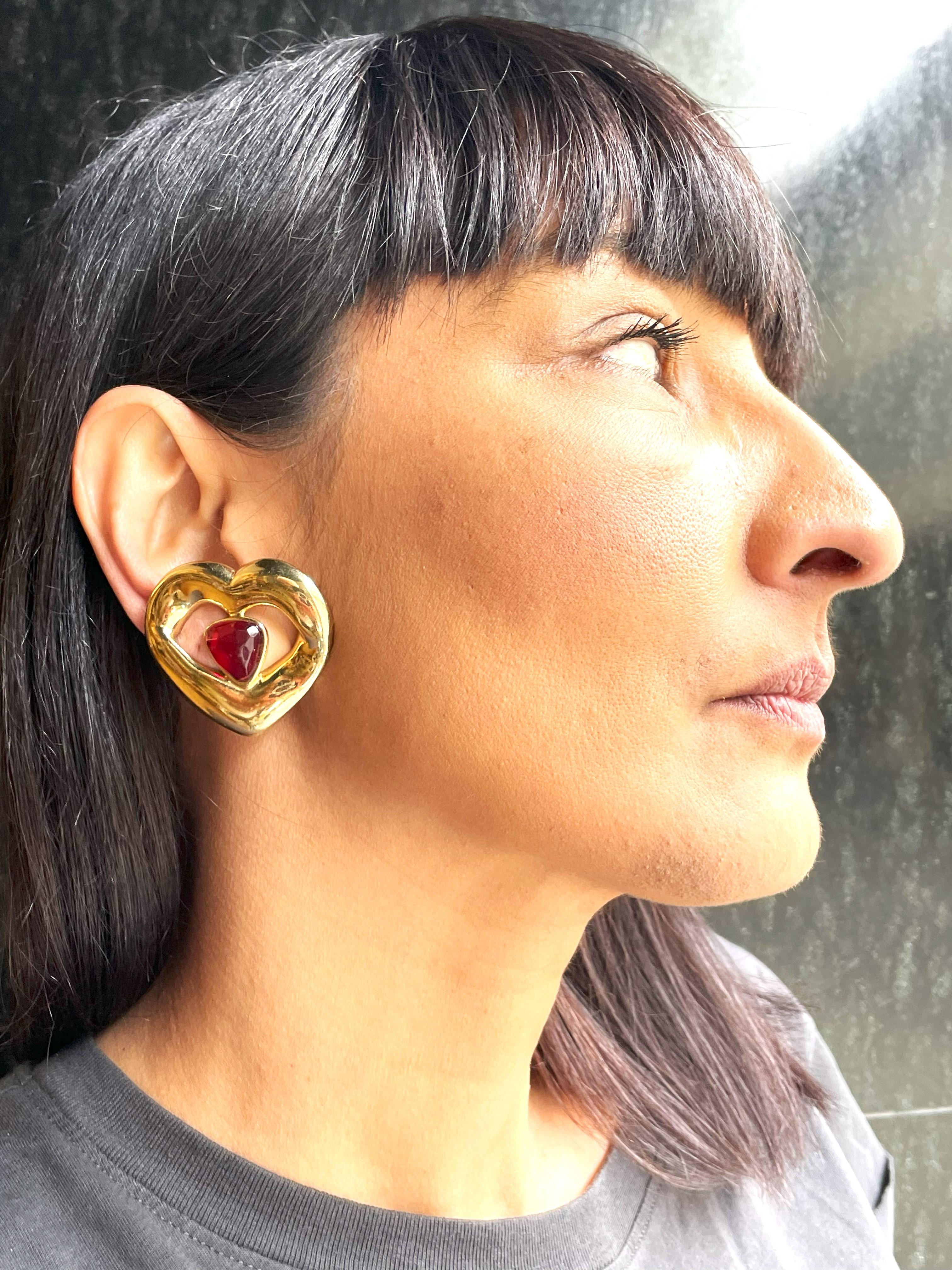ORECCHINO A CLIP CON CUORE TRAFORATO DI YVES SANT LAURENT (MADE IN FRANCE) CON UN CUORE ROSSO INCASTONATO AL CENTRO.

Questo fermaglio per orecchie è composto da 3 forme di cuore, la cornice esterna in oro - quella traforata fa anche da cuore e il