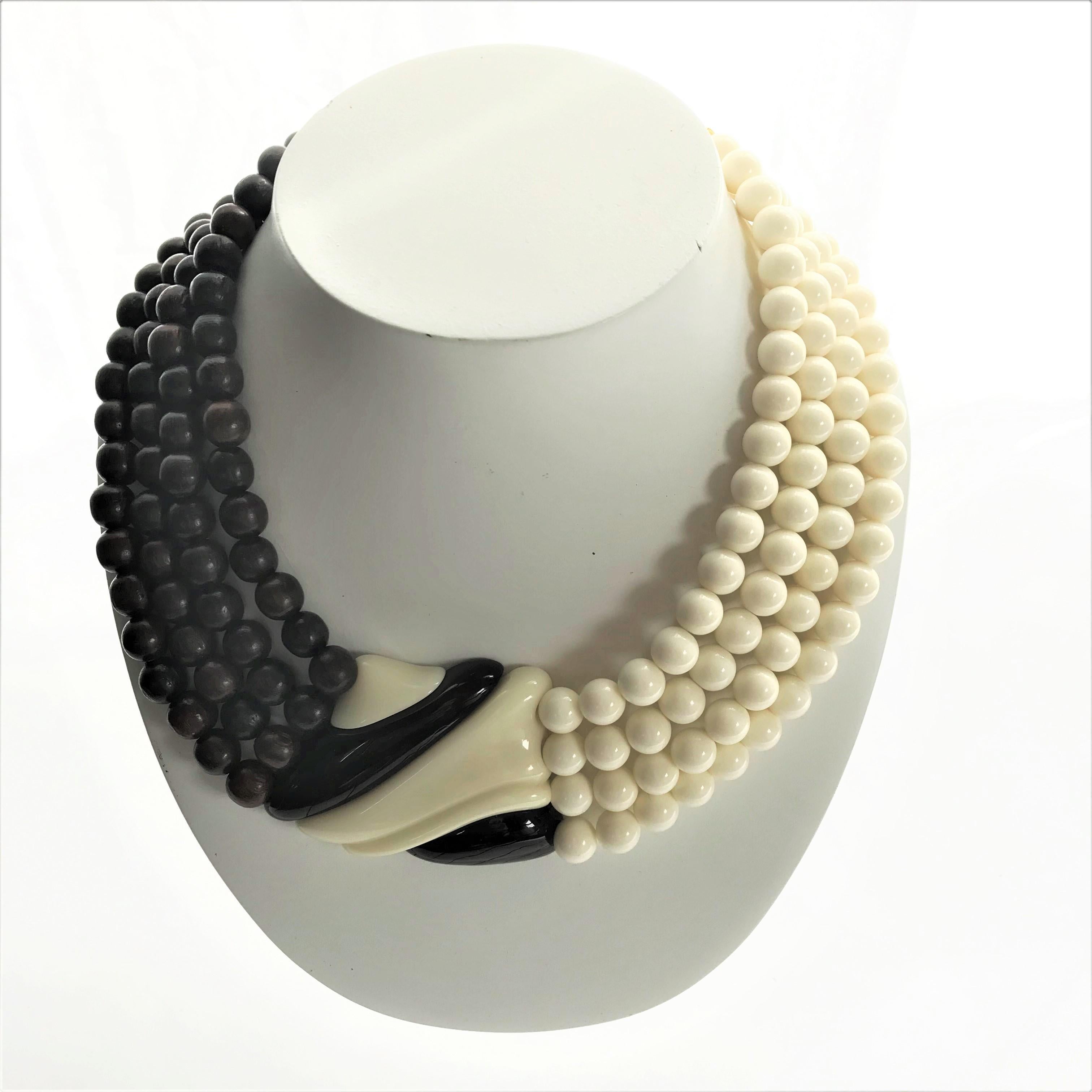 Iconic Yves Sant Laurent necklace with matching ear clip. One half of the chain consists of brown wooden balls, the other side of ivory colored plastic balls. In the middle a part consisting of the colors of the balls on both sides. 
Measurements: