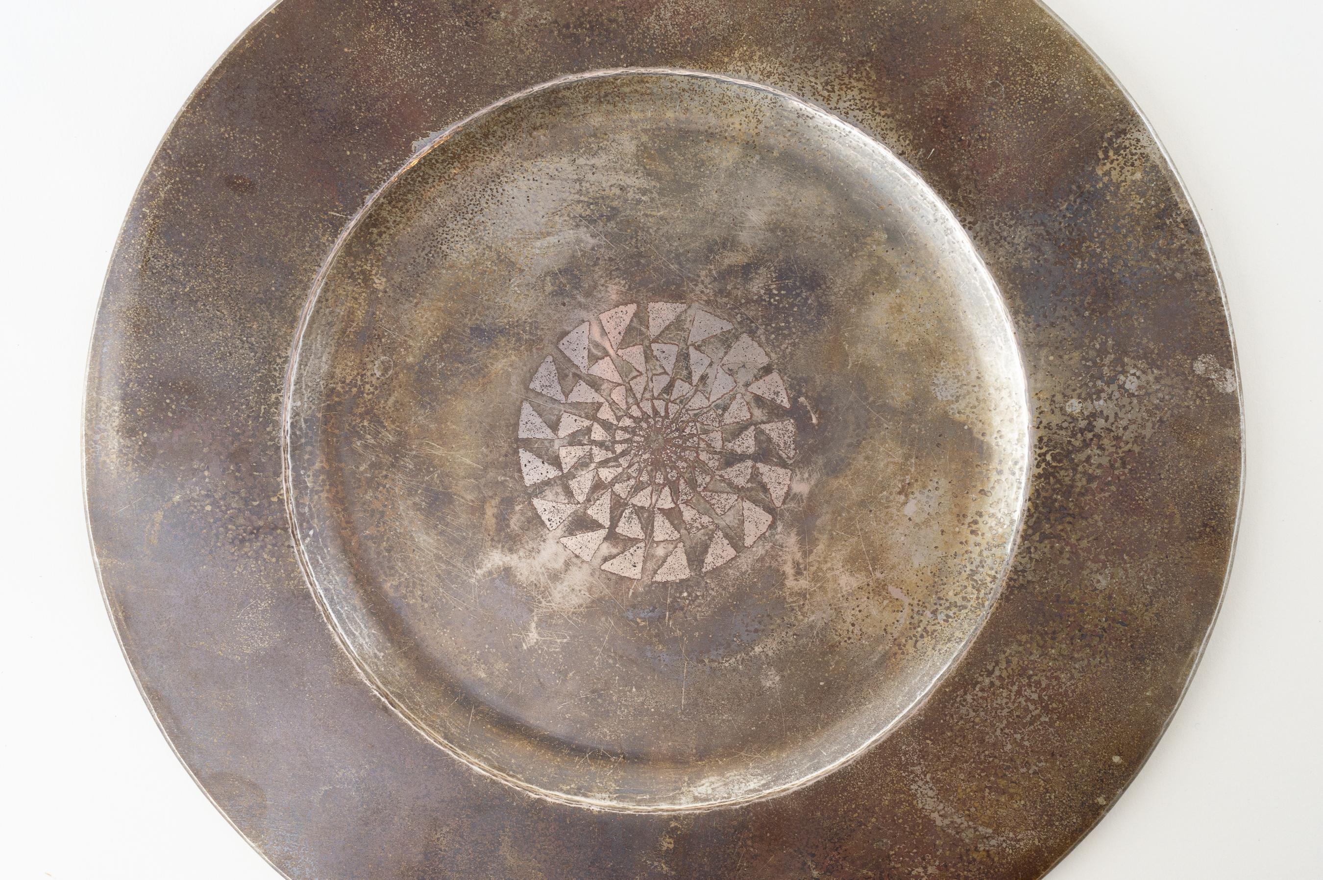 A large, circular nickeled silver platter decorated with a central geometric rosette composed of silver leaf. Strong Patina. Impressed “Y. DUCHAMPS/G. LACROIX” at underside.