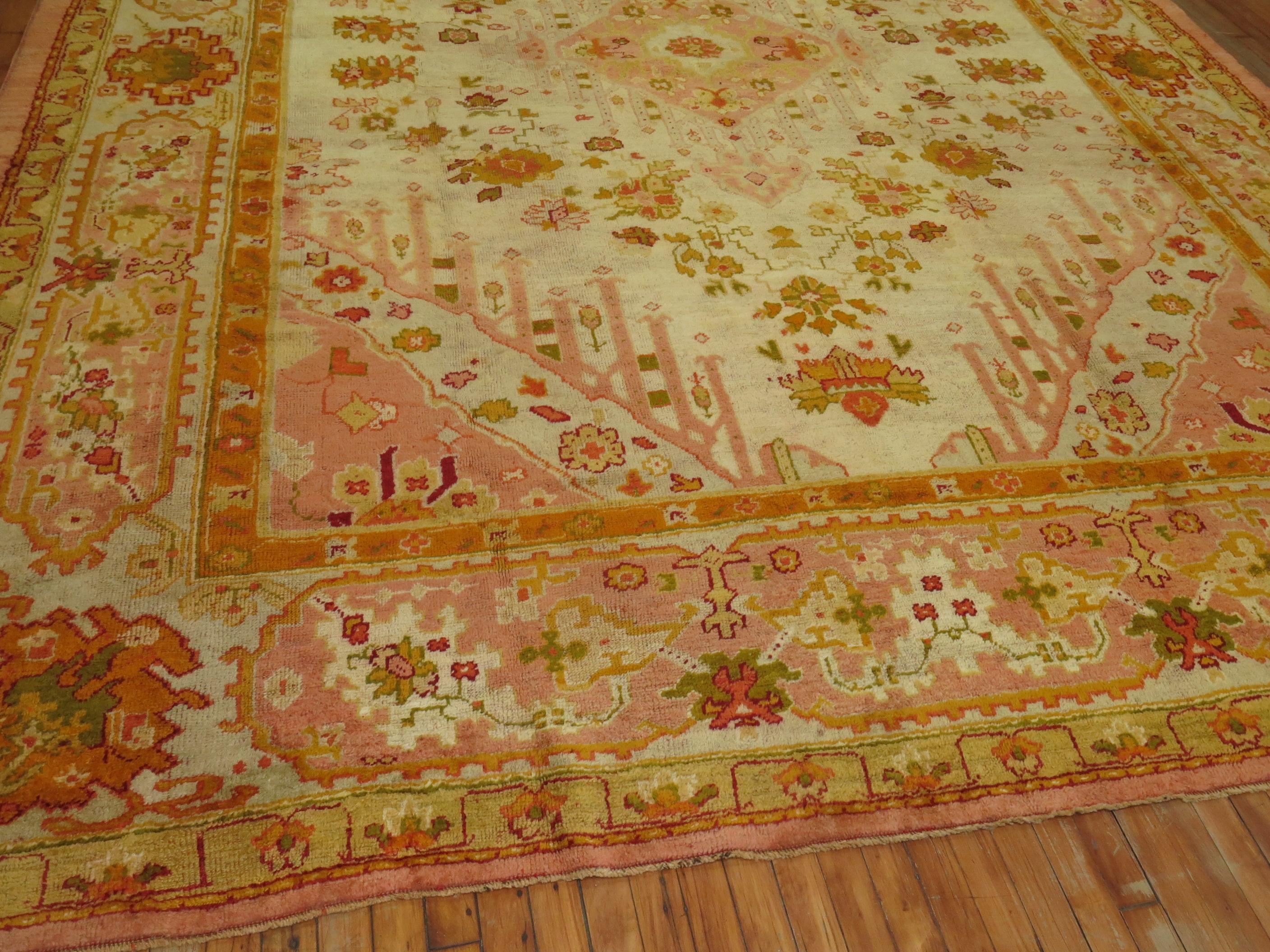An early 20th-century room size Antique Turkish Oushak rug in predominantly ivory field, dominant accents in fire orange and pink

Measures: 10'3'' x 13'4''

Oushak rugs originated in the small town of Oushak in west-central Anatolia, today just