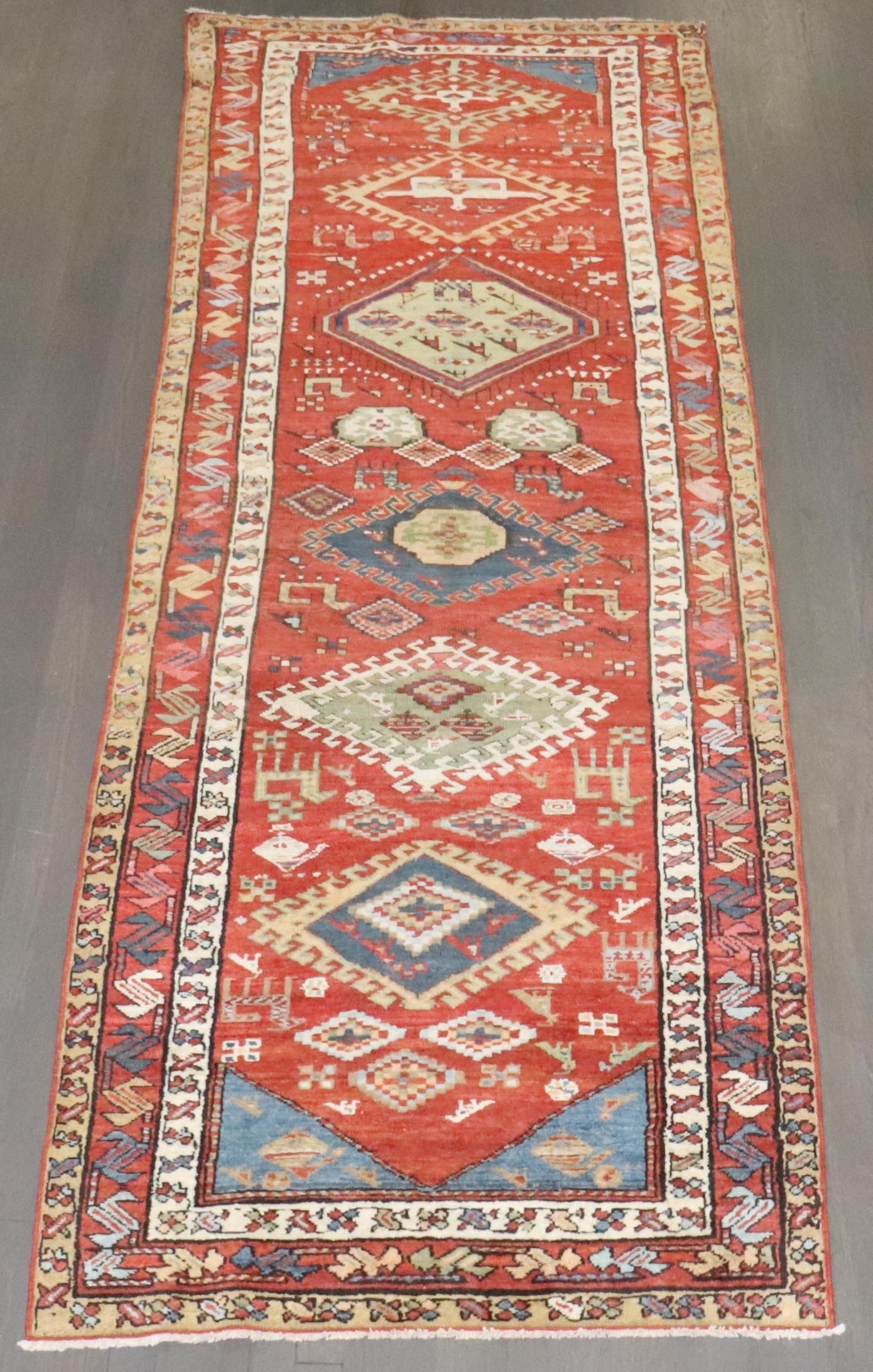 Vollfloriger geometrischer antiker nordwestpersischer Läufer mit rotem Feld, das mit bunten Medaillons, mehreren Bordüren und französisch-blauen Eckzwickeln besetzt ist, um 1920.

Maße: 3'6