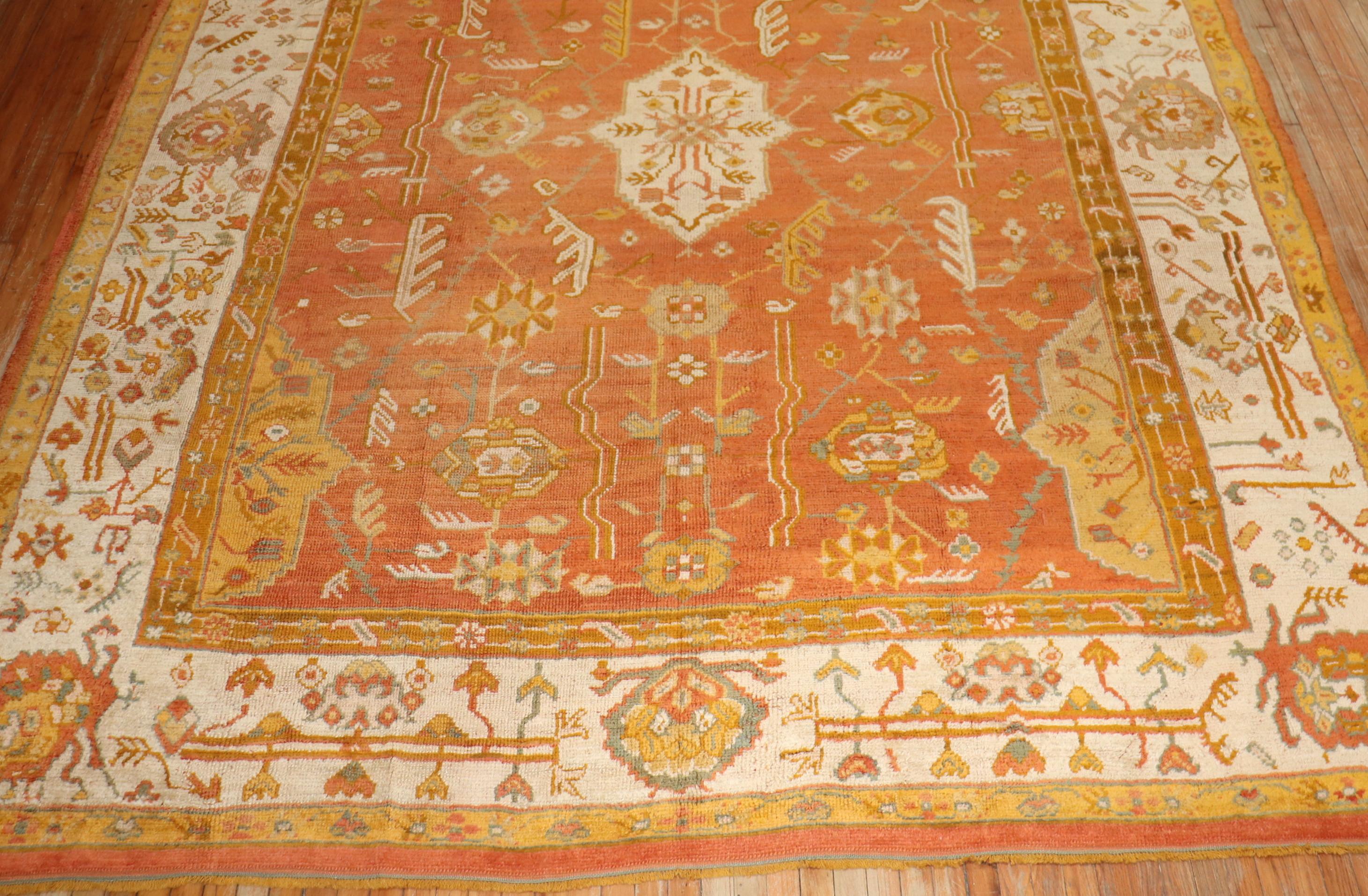An early 20th-century orange field antique Oushak 

Measures: 10'4” x 13'2”.