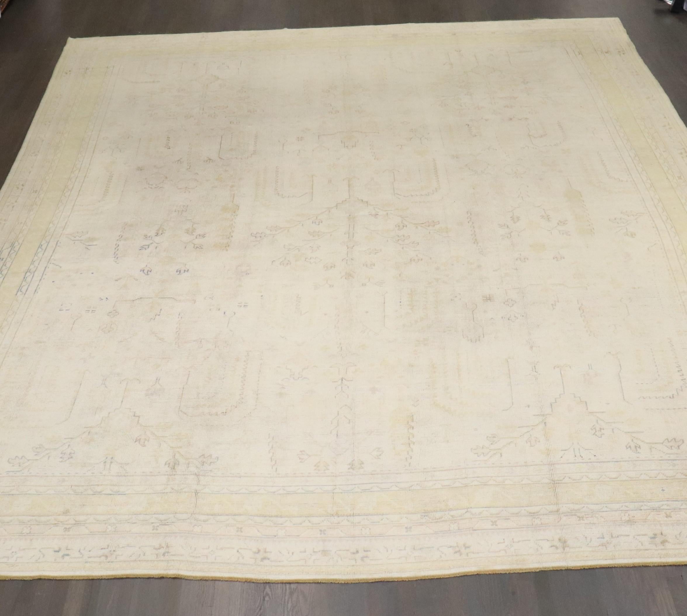 an early 20th century Pale Ivory field Turkish Oushak Rug that has been antique washed. some yellow and blue dominant accent colors

Details
rug no.	j3812
size	13' 2