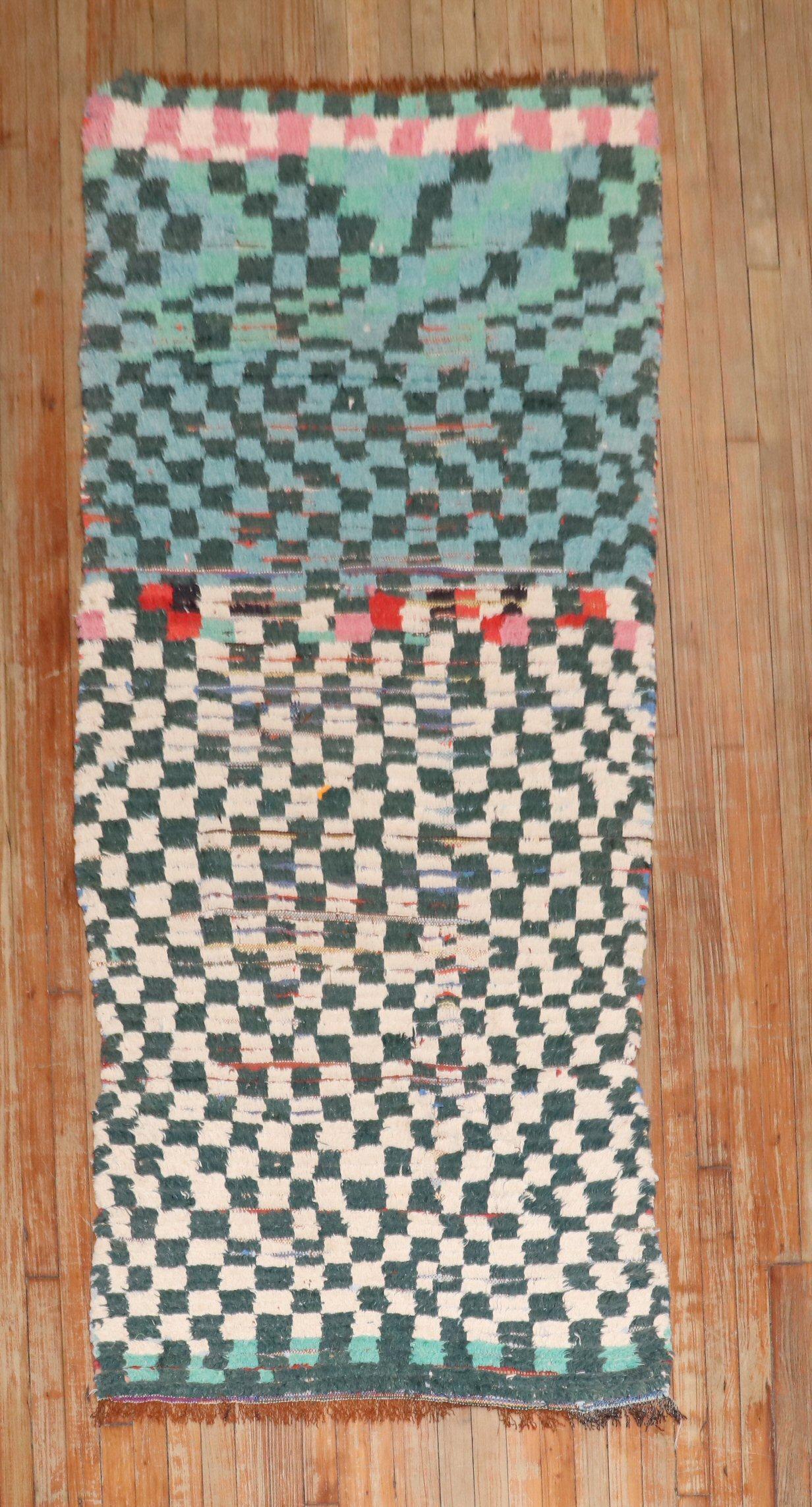 Mid 20th century moroccan small runner with the ever recurring archetypical checkerboard design made in this case from industrial yarns. The traces of wear create a kind of double layer between the cool blue / green / petrol shades of the pile + the