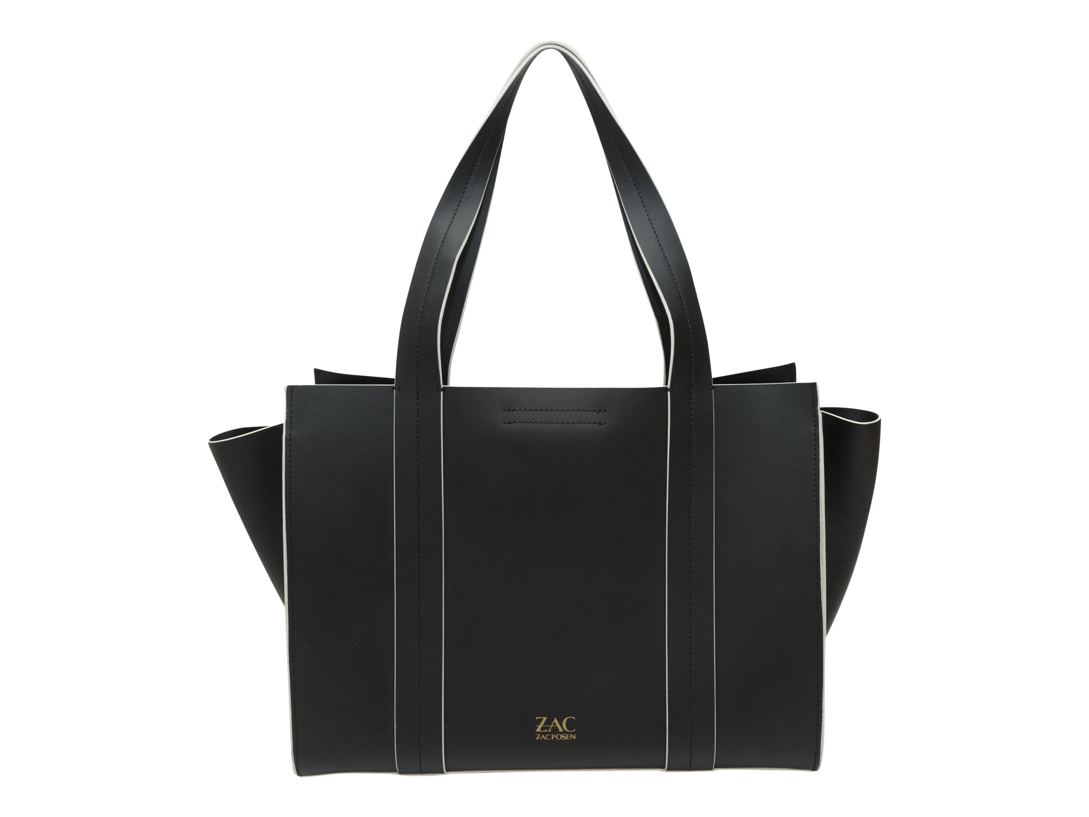 Product details: Black leather handbag by Zac Posen. White trim throughout. Gold-tone hardware. Closure at front. 14