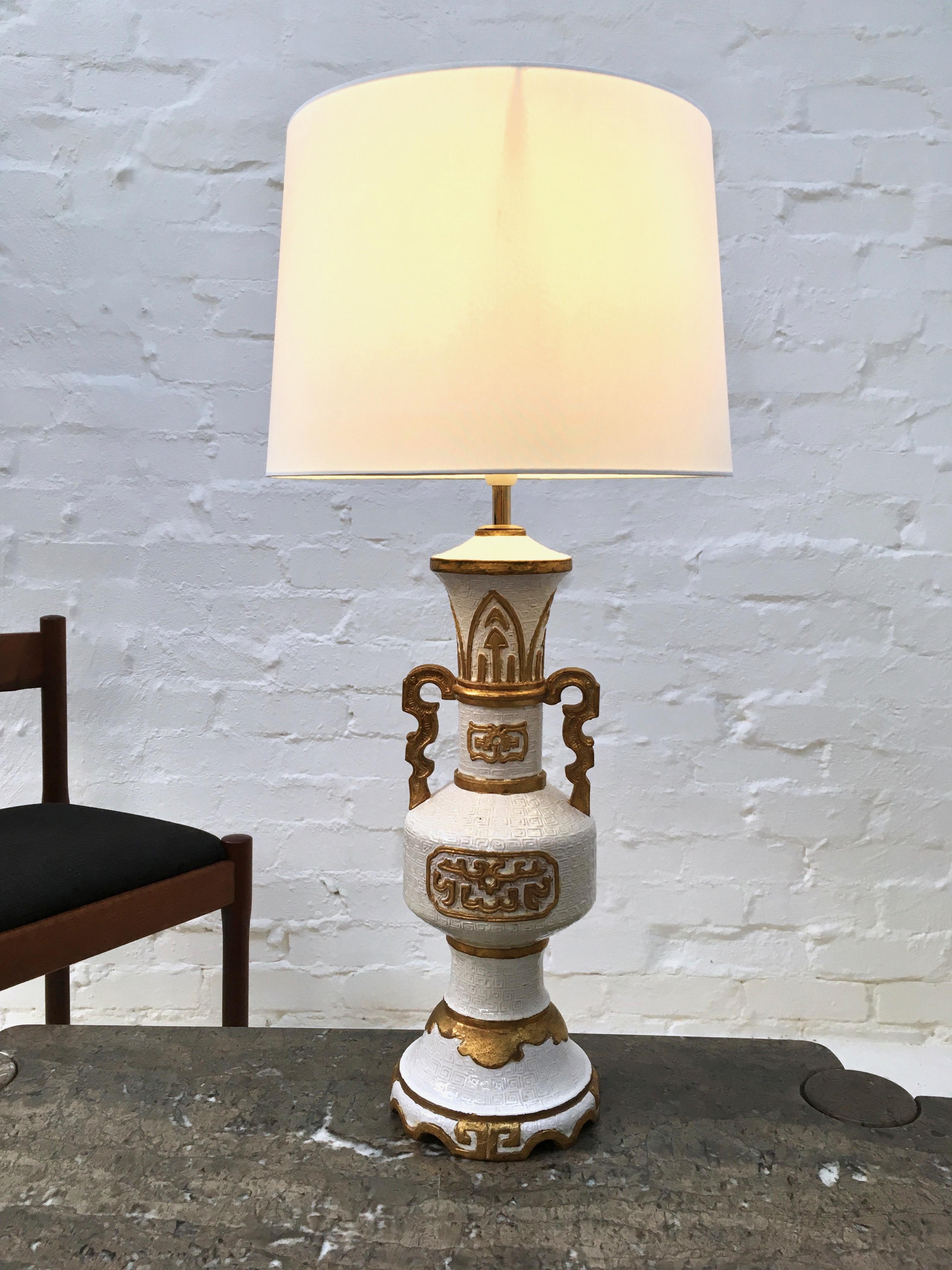 A large Hollywood Regency lamp with stylised decoration, standing 32 inches tall to the top of the shade. In keeping with the 1940s-1950s decorative style which saw large lamps move into the domestic market, this lamp is influenced by the scale and