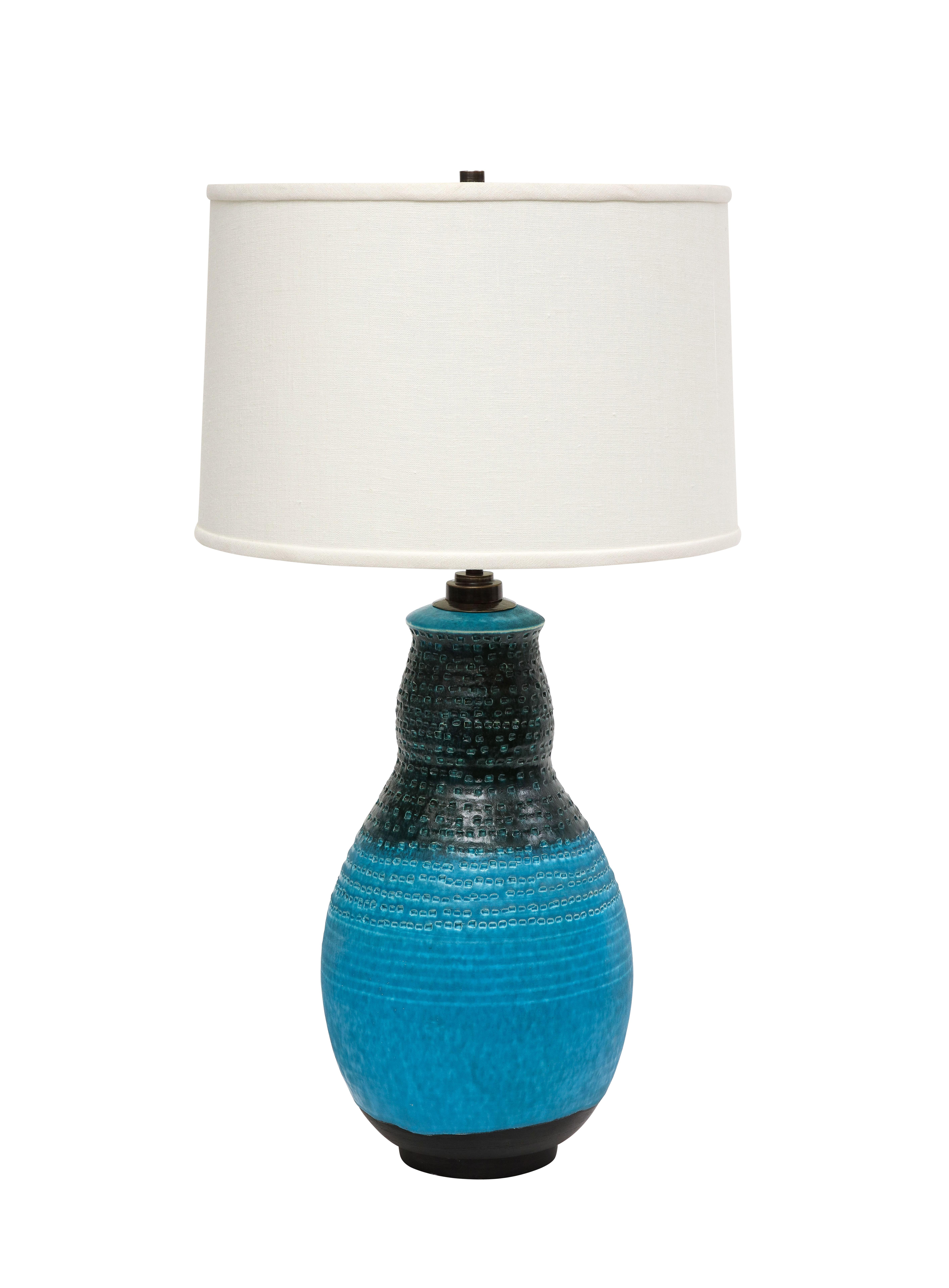 Alvino Bagni table lamp, ceramic, blue, black, impressed. Large gourd form hand thrown pottery lamp with footed base. Glazed in blue and black and decorated with horizontal rows of hand tooled rectangular impressions. The electrical fittings were