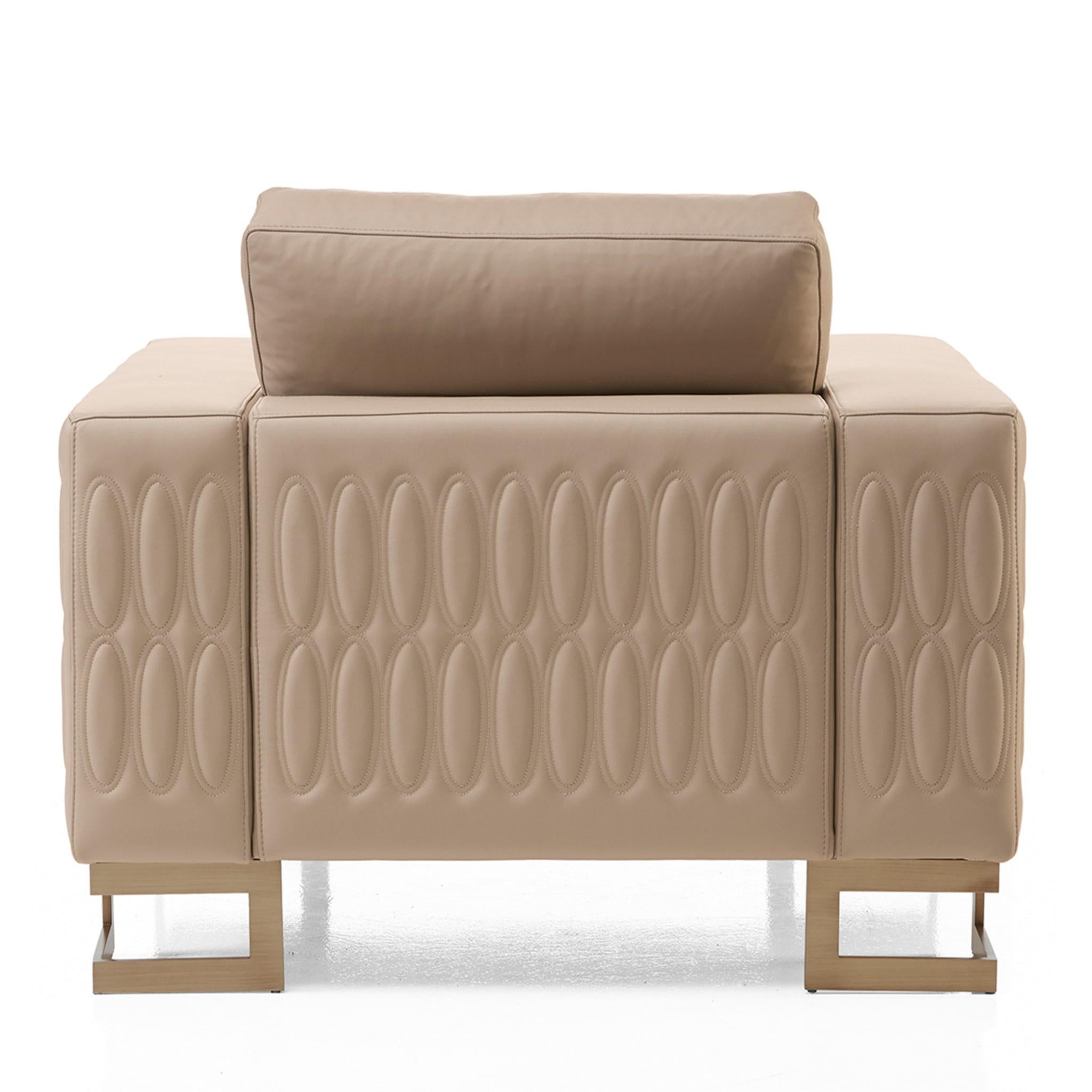 Assorted geometric inspirations harmoniously coexist in this sophisticated armchair luxuriously covered in fine beige leather. A repetitive quilted pattern of ovals adorns the sides and the coordinated cushion, a choice further underscoring the