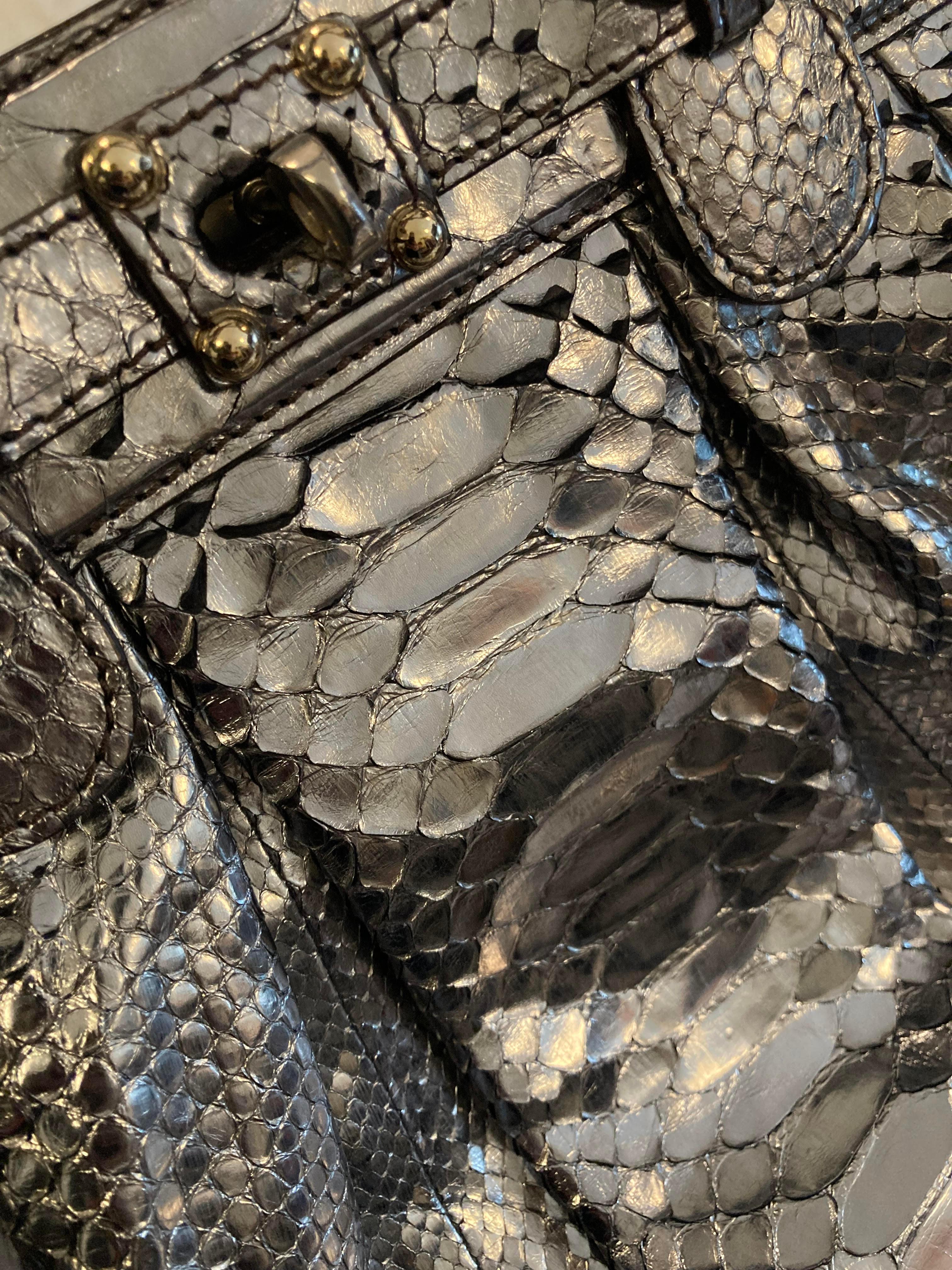 Metallic silver python bag from Zagliani. Featuring a soft, rounded body with structured, frame top and double rolled top handles also in metallic silver python. Straps are long enough for shoulder carry. Twist lock closure is held in place by four
