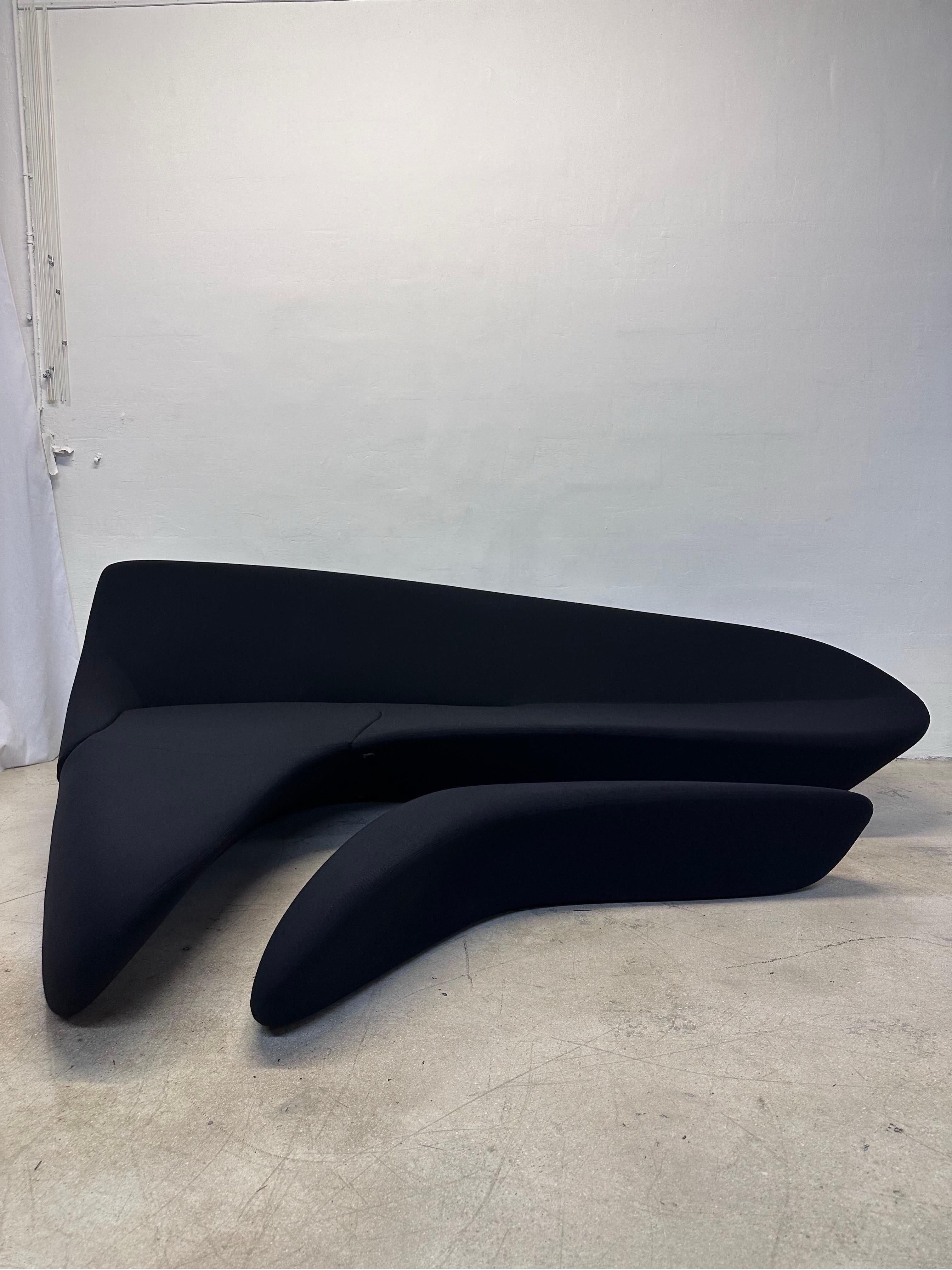 Sculptural curvilinear sofa and foot rest by renowned architect and designer Zaha Hadid.  The steel and foam frame is covered in a black cotton stetch fabric. The footrest fits snugly into the void beneath the sofa.  The collaboration between Zaha