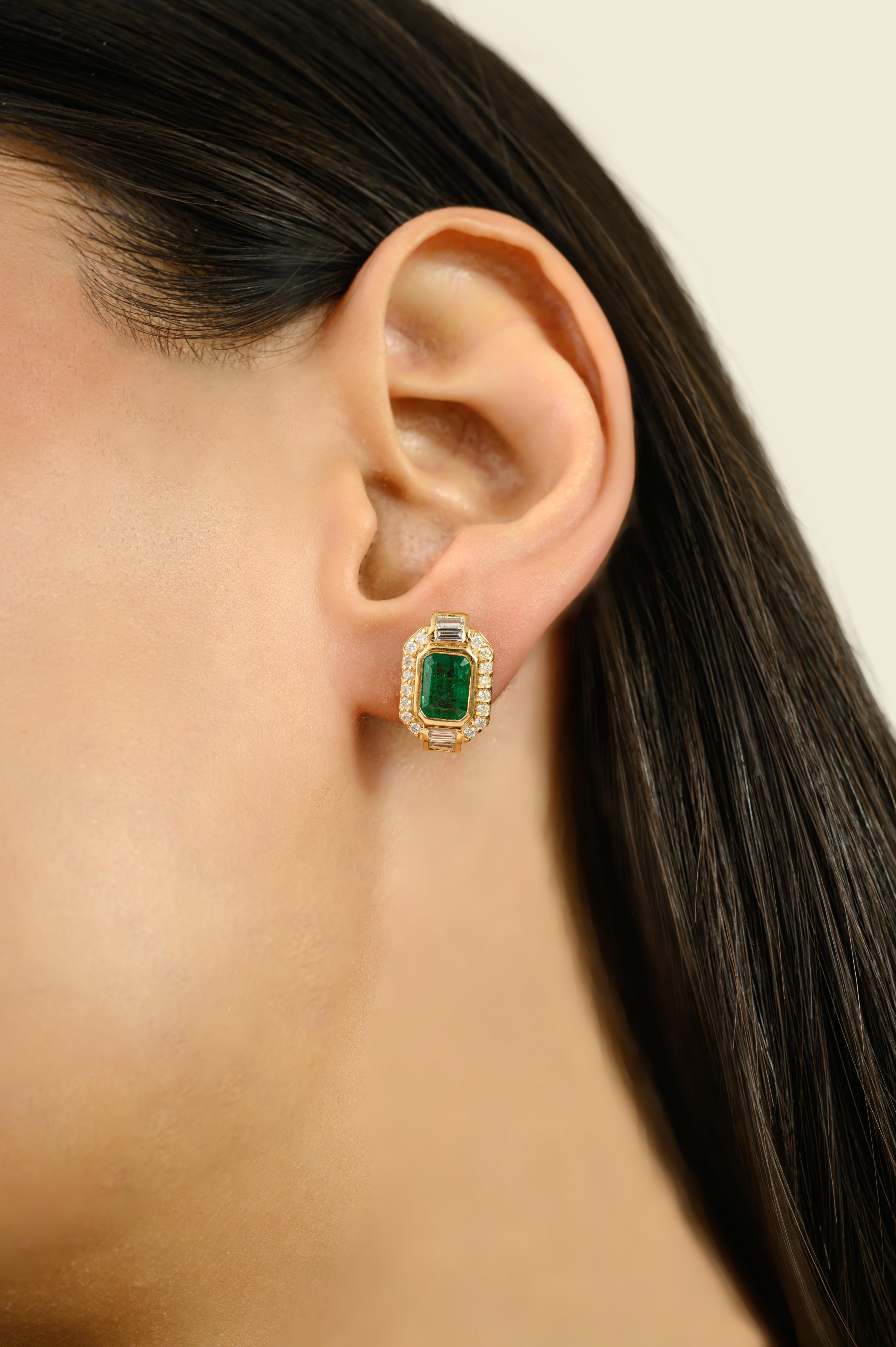 These Zambian Emerald Halo Stud Earrings with Baguette & Round Diamond 18k Yellow Gold. Featuring vibrant emerald-cut green emeralds at the center, each earring is beautifully framed by a halo of round brilliant diamonds, accented with baguette