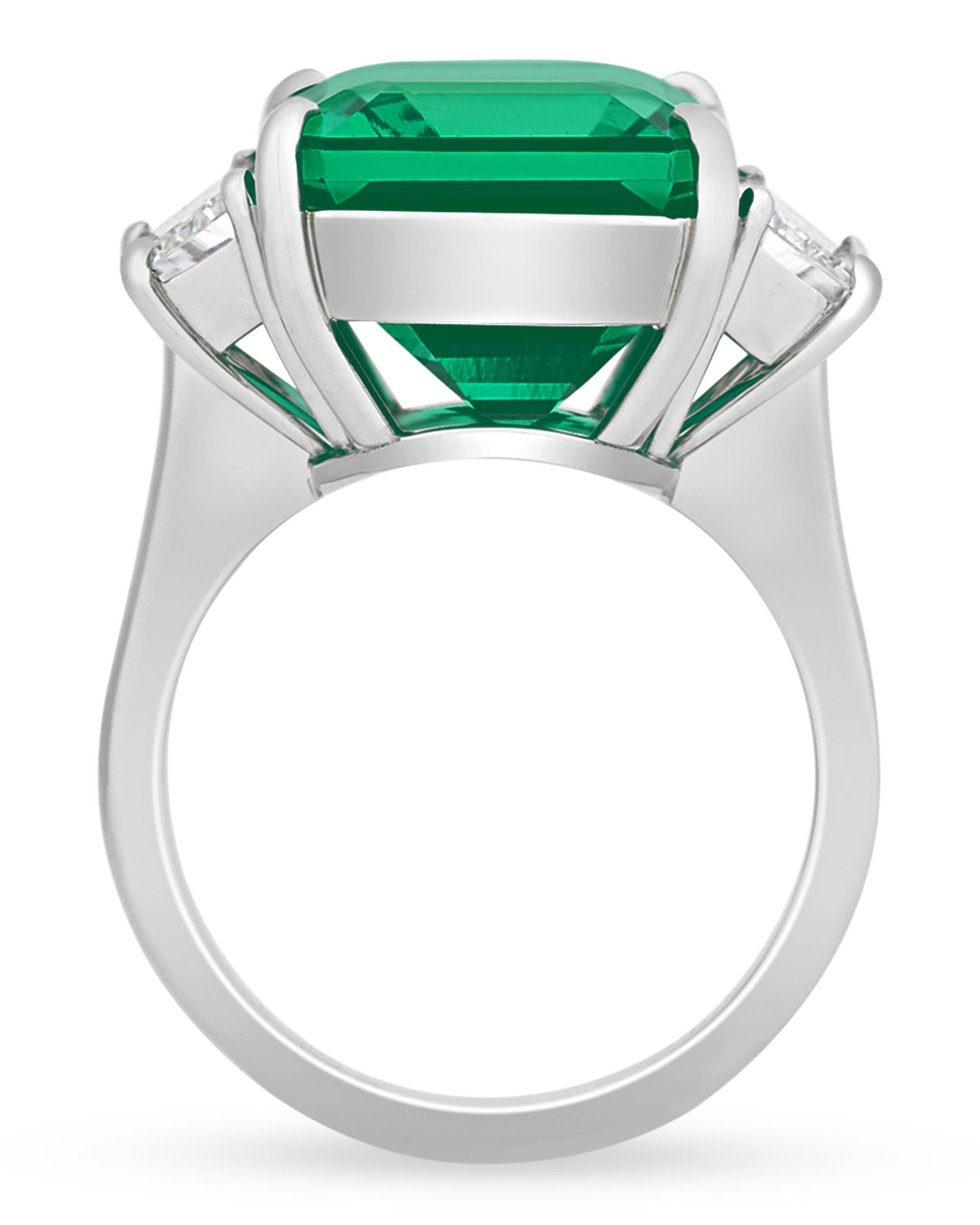 Displaying a striking vivid green color, a 12.47-carat octagonal step-cut emerald lies at the center of this distinctive ring. This gemstone is certified by GemResearch Swisslabs and C. Dunaigre as being Zambian in origin. Zambian emerald mines are