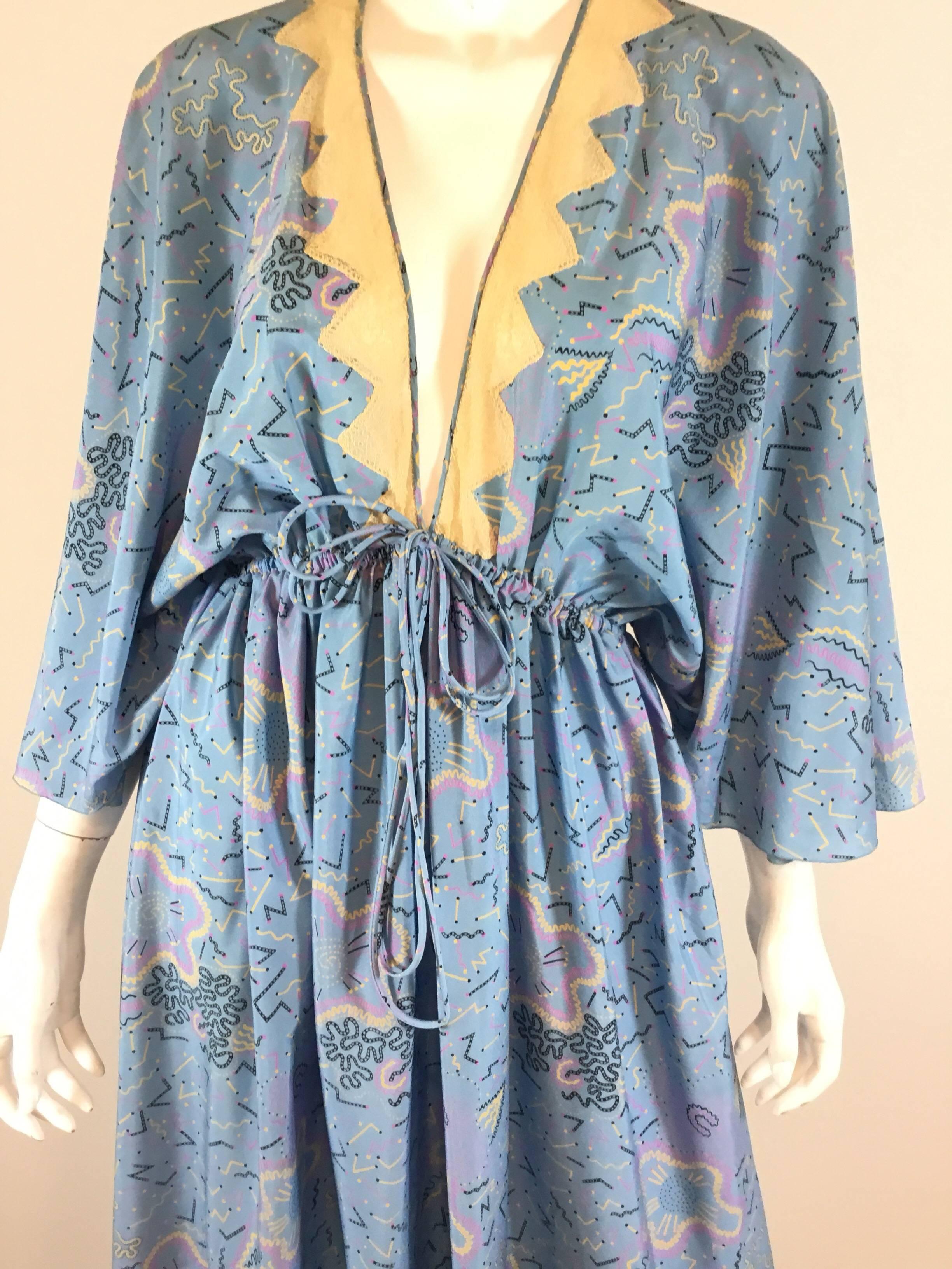 Zandra Rhodes vintage caftan dress features a blue multicolored print throughout with a lace trim along the neckline. Dress has an elasticized waist that also has a decorative waist tie closure. Dress is in great condition with normal wears