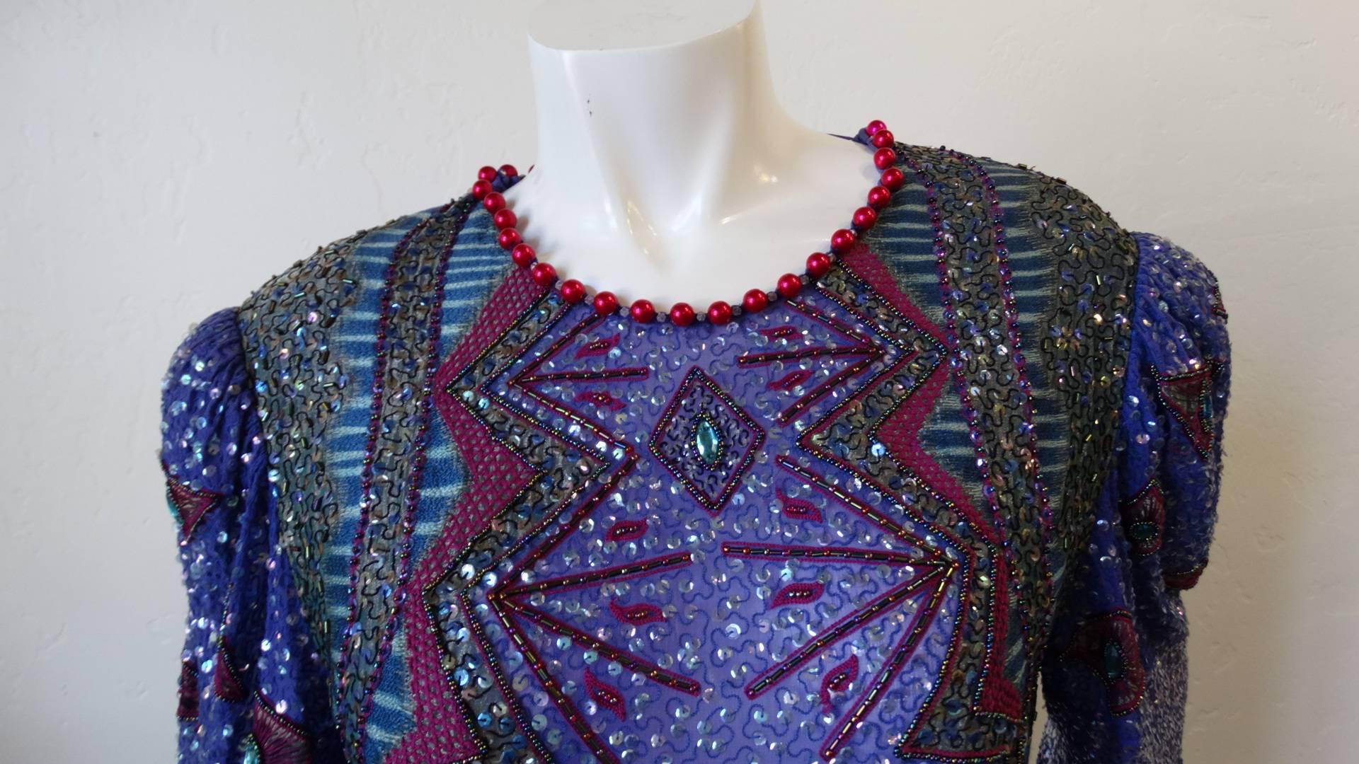 The most amazing embellished dress from iconic 1980s designer Zandra Rhodes! Constructed from a violet sequined silk fabric and absolutely covered in rhinestones and intricate beading! Accented with red round beads around the neckline. Kaftan style