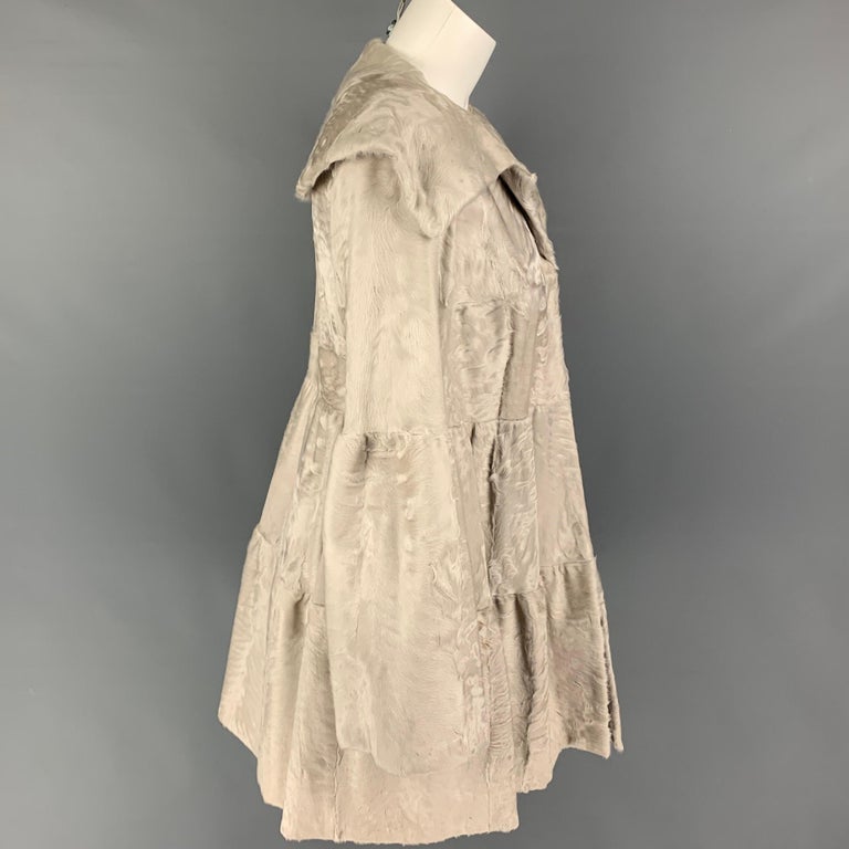 ZANDRA RHODES coat comes in a light gra lamb shearling with a full liner featuring a large lapel, slit pockets, and a hook & eye closure. 

Good Pre-Owned Condition. Light discoloration at collar. As-Is.
Marked: Size tag