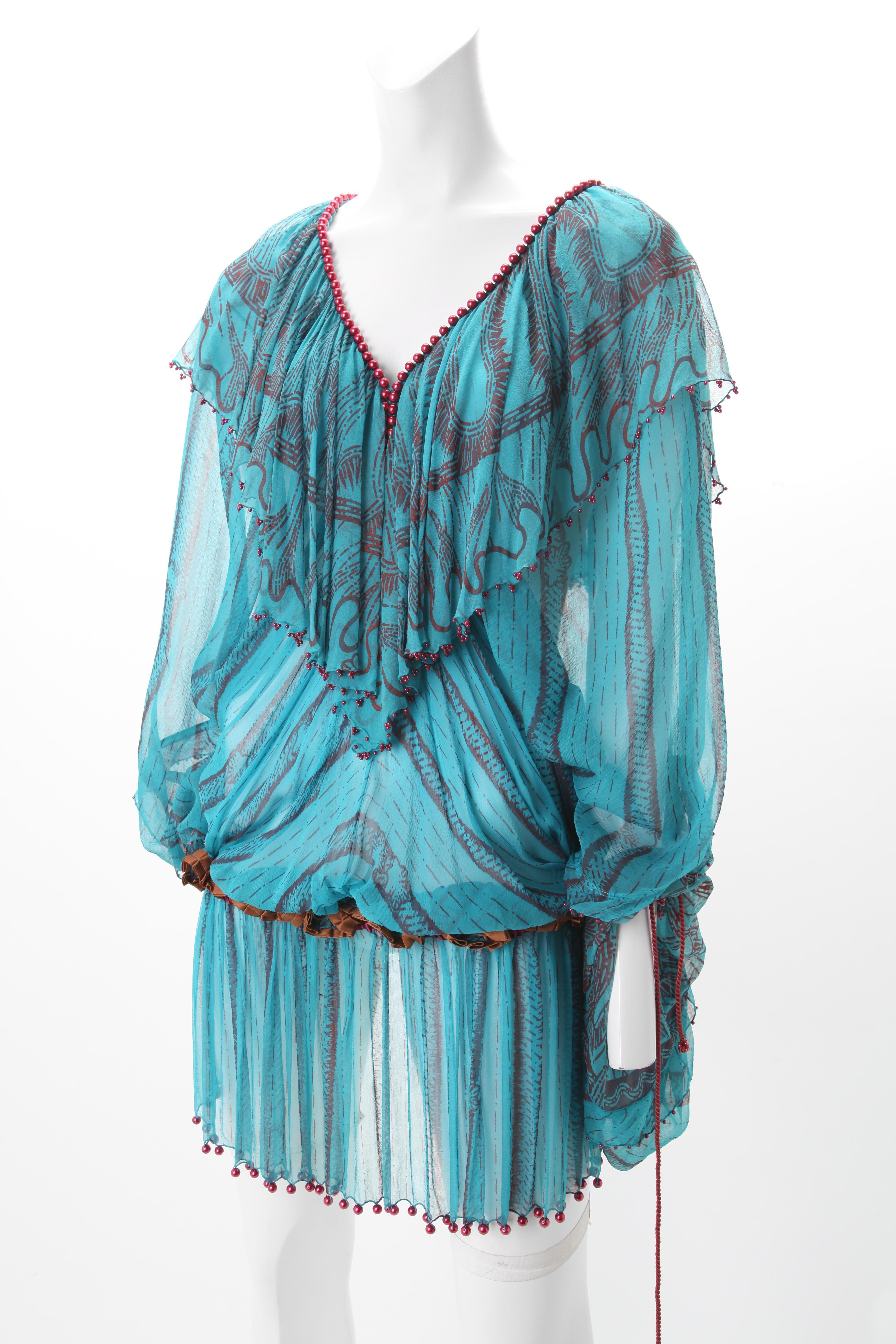 Zandra Rhodes Teal Printed Dress with Red Beading, c.1980s
Zandra Rhodes teal sheer chiffon dress with maroon paisley print design throughout. Dress features a self material V-Shape overlay at neckline both are outlined by red beads. Dress has a