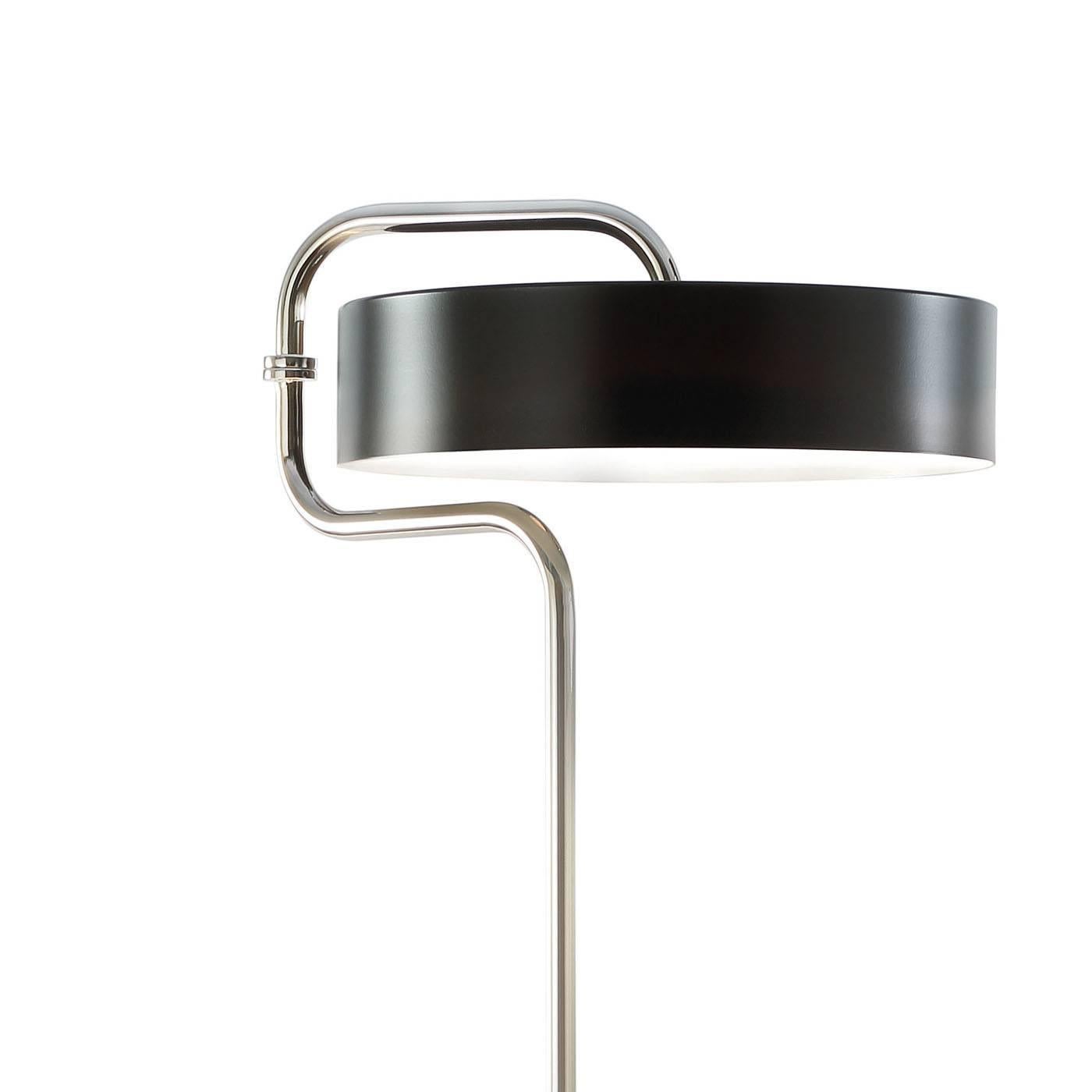 Elegant and modern, this floor lamp features geometric shapes and a sophisticated silhouette consisting of a round base supporting an elongated shaft that curves at the top to make room for the shade, in the shape of a large cylinder. The entire