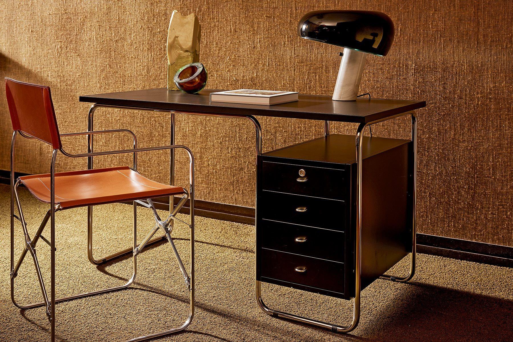 Writing desk. 18/8 stainless steel tubular frame. Top and storage unit in medium density fiberboard finished with scratch resistant embossing in the colours talc or black. The top can be with cowhide pigmentato 90 insert. The storage unit is