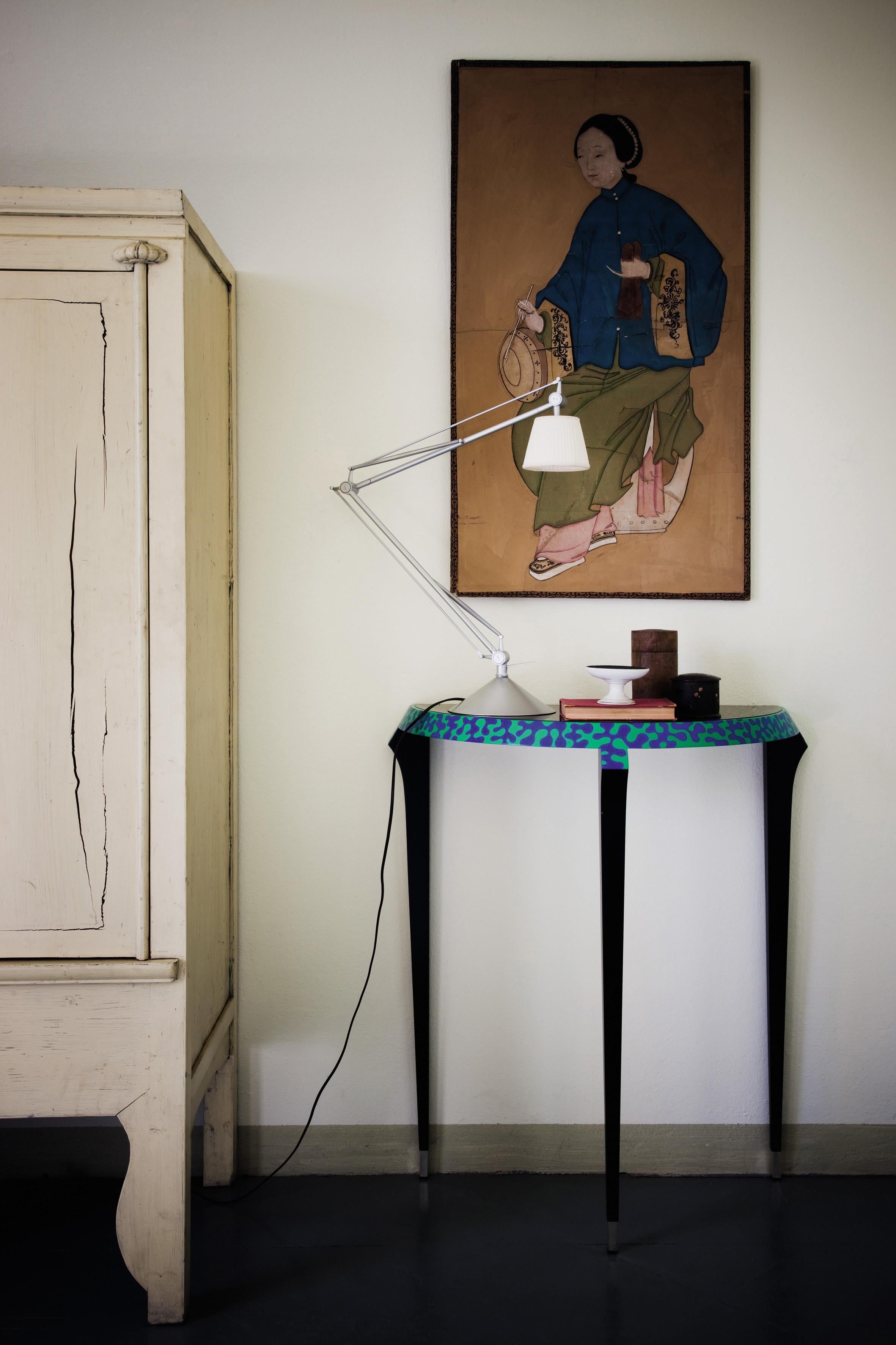 Signed original. Frame in black lacquered wood. Hand-decorated edge in blue and green. Feet in silver plated brass. Top in black painted plate glass. Designed by Alessandro Mendini in 1984.

A small console, Agrilo, and a large table, Macaone,
