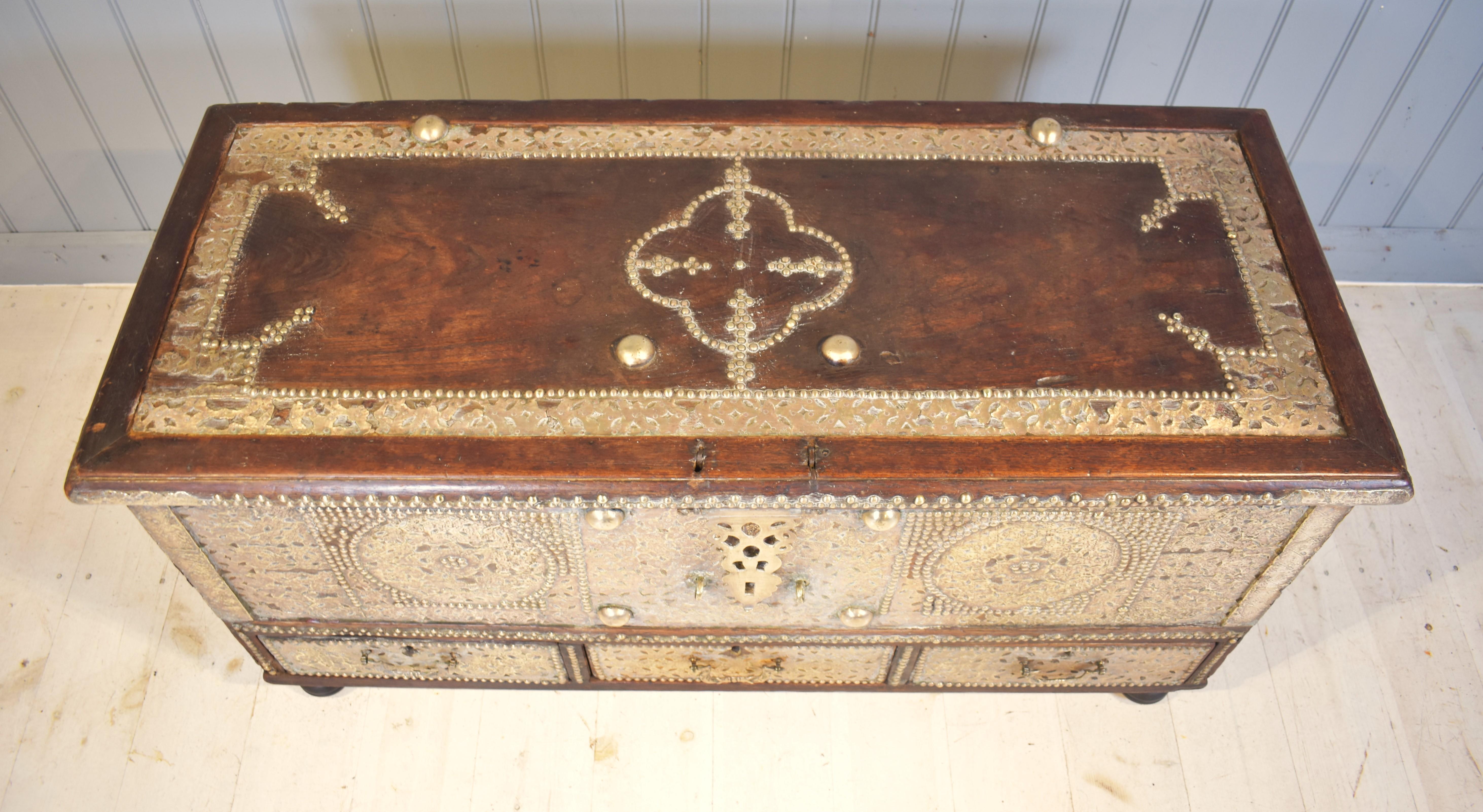 Coffre de Zanzibar très décoré en laiton clouté et fretté, milieu du 19e siècle. Fabriqué en teck et très lourd, l'intérieur est doté d'une boîte à bougies. Les trois poignées de tiroir, les poignées de transport latérales, les charnières en laiton