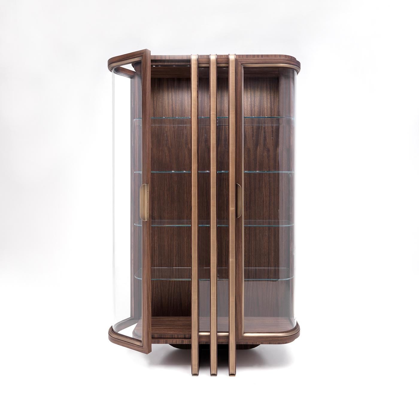 The perfect accent piece for a classic or modern decor, this precious display cabinet features an imposing zebra wood frame. The curved profile of the front is traced by the two glass doors extending to the wooden back to set the attention on the