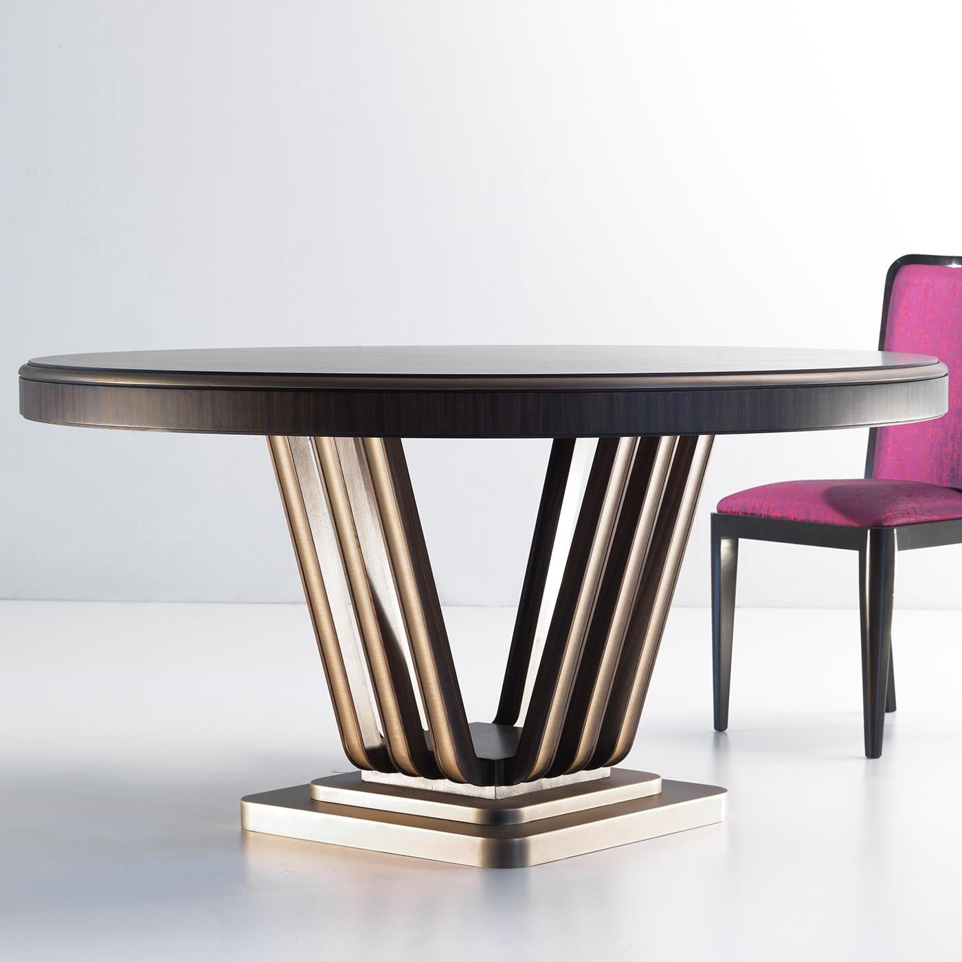 Bold volumes following elegant paths. The striking design marking this imposing dining table blends materials as zebra wood and brass components that lend the table its sober dose of light. The circular top flaunting the wood's typical veining rests