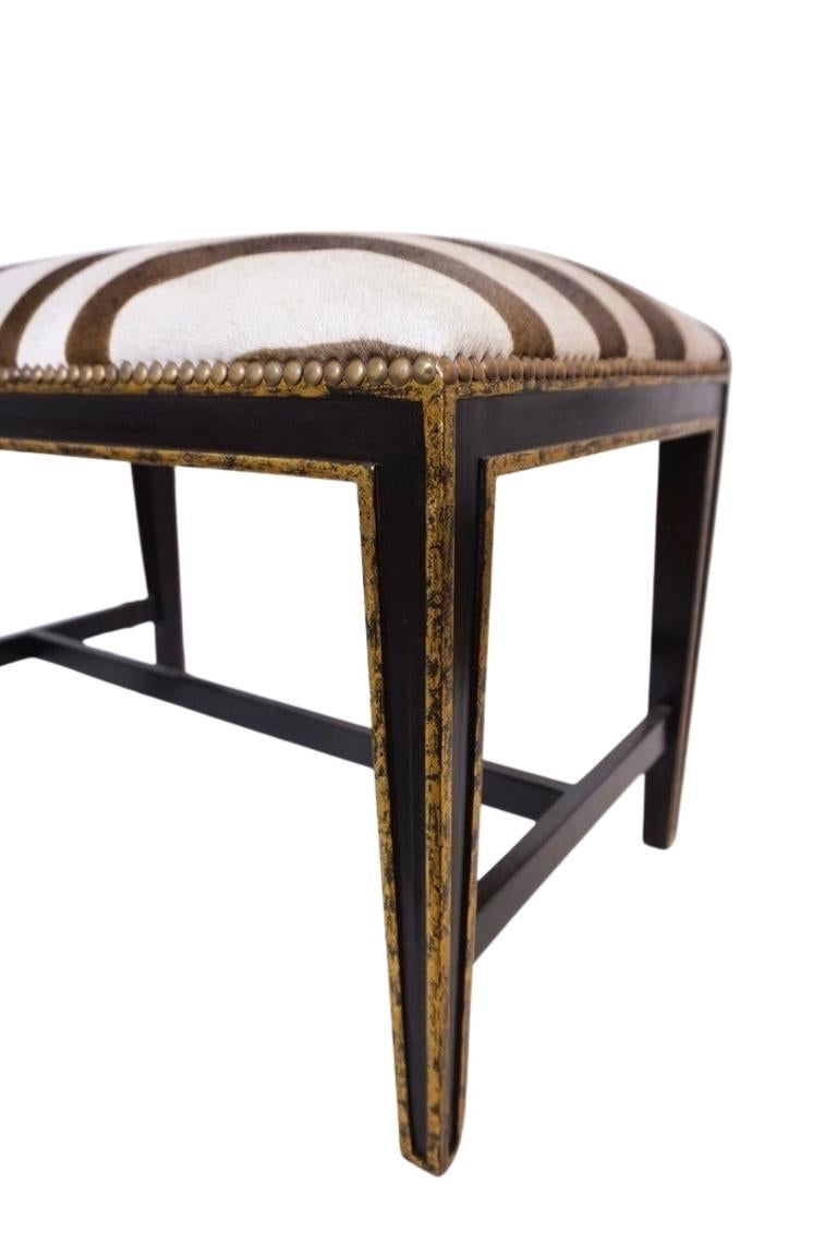 This luxe little bench features a zebra-upholstered cushion and gilded legs with nailhead detailing. Use in an entryway, at the foot of your bed, or in any corner of your home that could use a little 