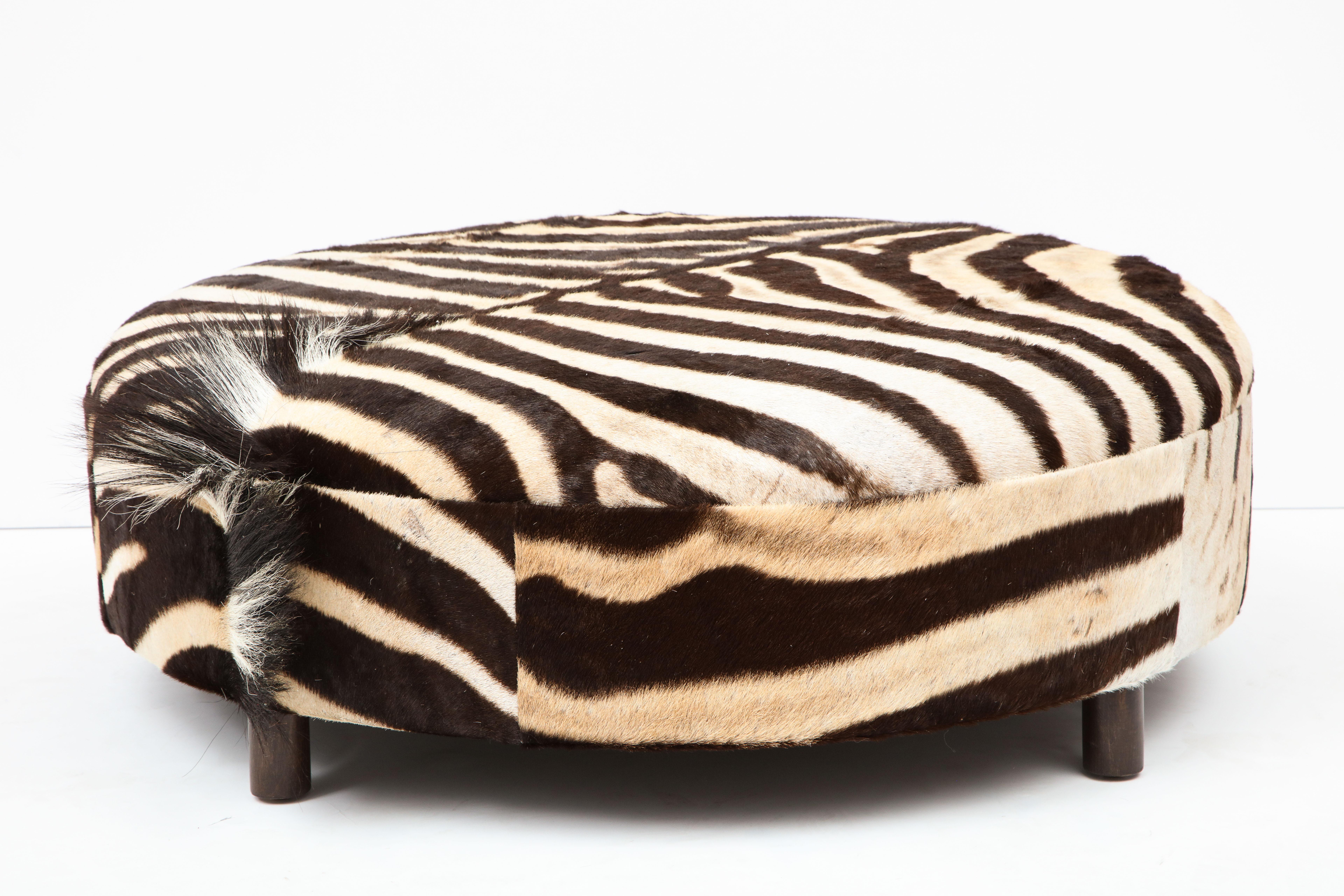 Decorative zebra hide ottoman. Zebra hides are from South Africa and the ottoman is made in NJ. Measures: diameter is 36 inches and height is 12 inches. The mane of the zebra is very decorative located on the side of the ottoman. The ottoman has