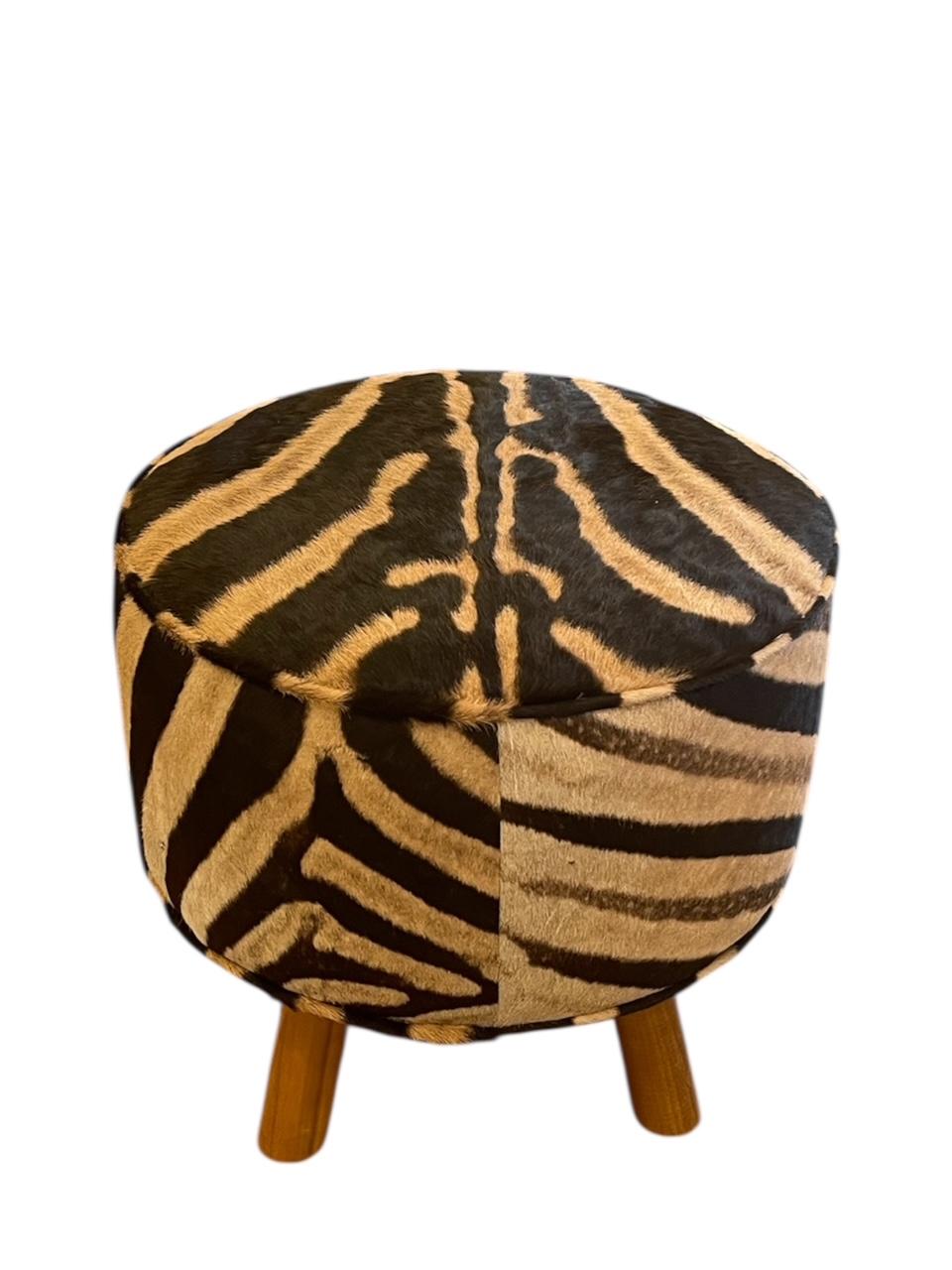 Dieser robuste Hocker mit 4 Beinen ist aus dem feinsten Zebrafell der südafrikanischen Savanne gefertigt. Dieses exotische Stück eignet sich perfekt, um jedem Raum Textur und Tiefe zu verleihen. Das Geheimnis und die Neugierde  Mit dem wunderschön