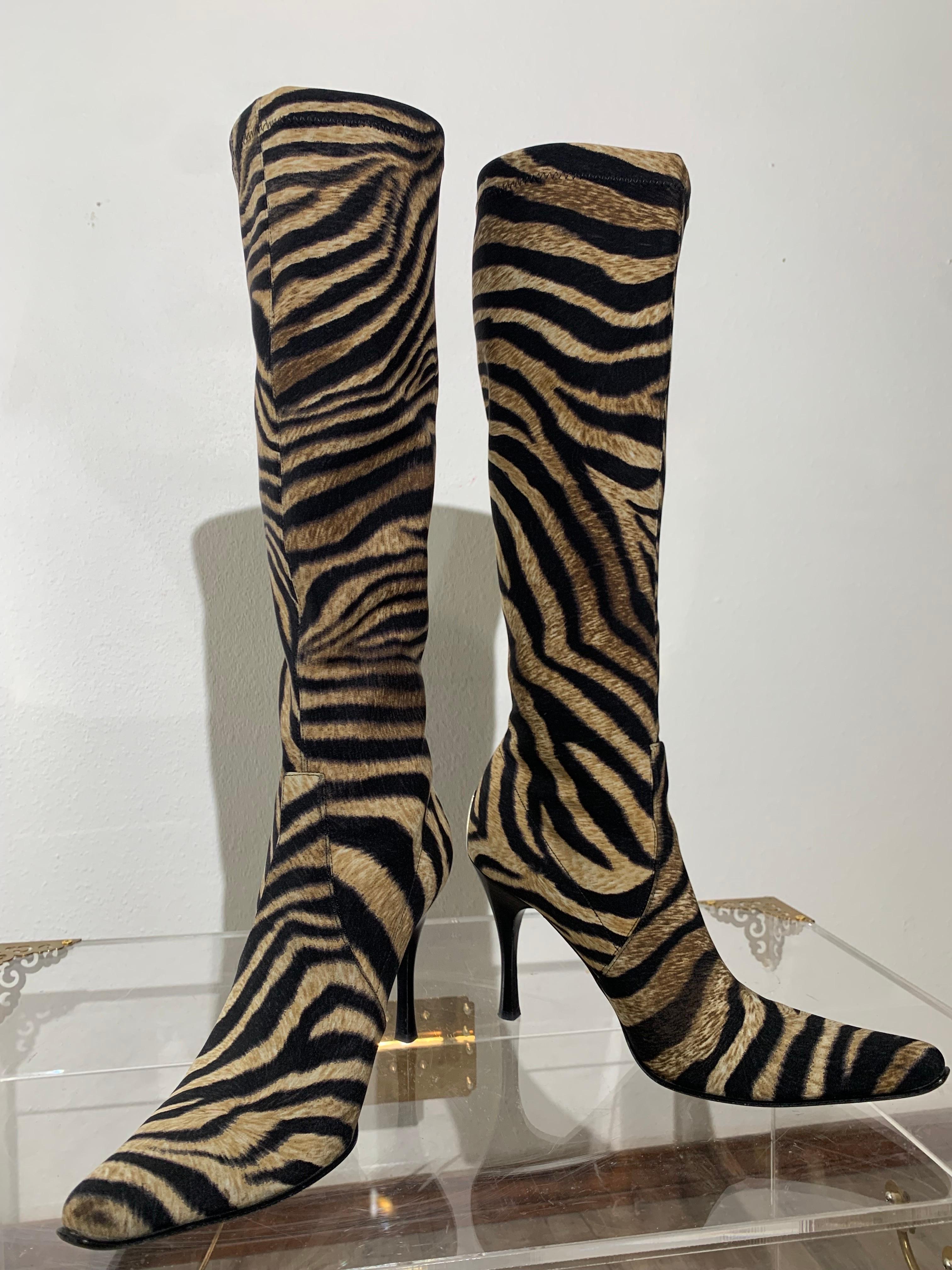 Botas elásticas hasta la rodilla con estampado de cebra:  Dramática punta afilada, tacón de aguja alto con una protección de metal plateado en la talonera. Un precioso estampado de cebra realmente detallado le da un aspecto exótico de lujo.  Suela