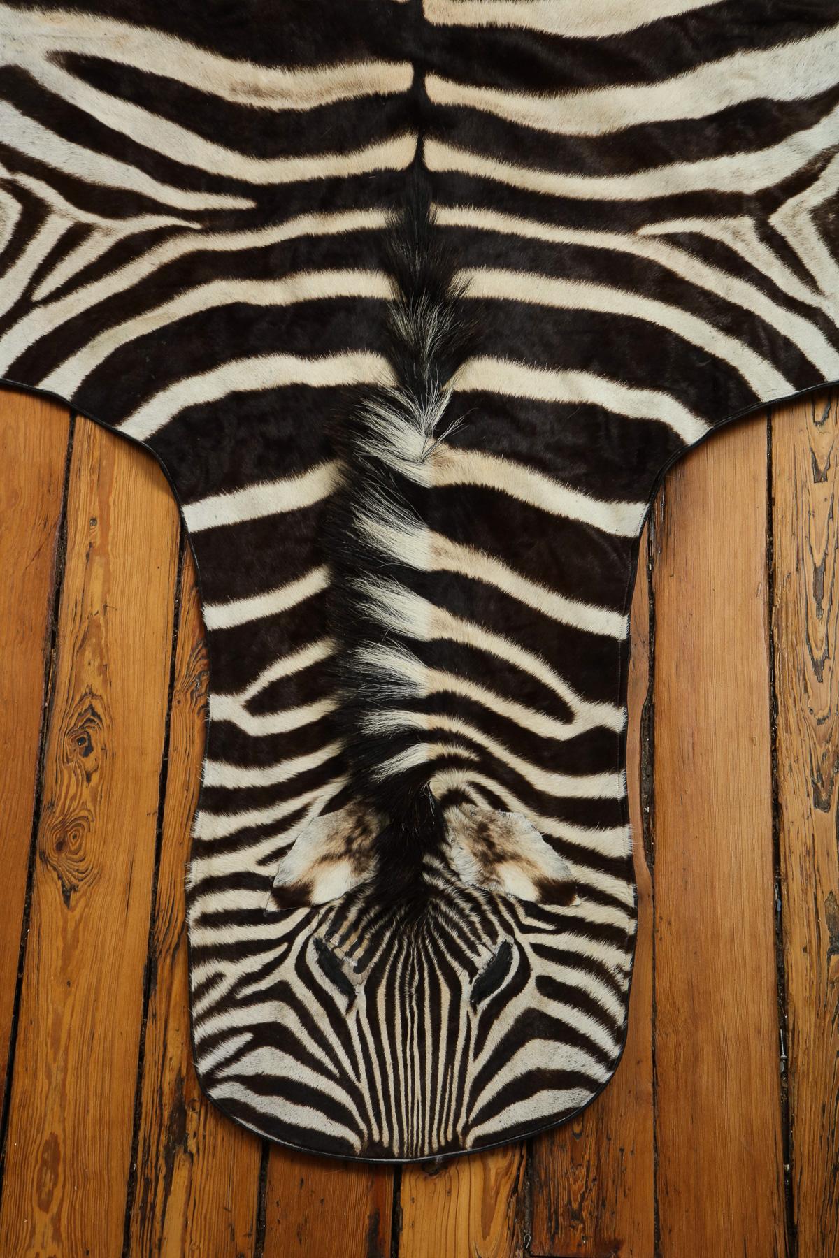 Beautiful zebra rug. This rug is extra white which is very hard to find. The hide has a wool backing and a leather trim all around.