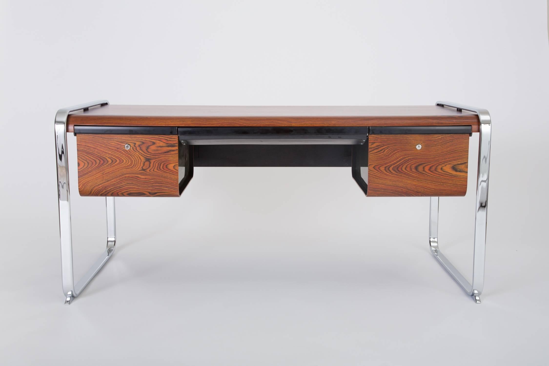 An executive desk from Peter Protzman's Tubular collection for Herman Miller. Manufactured only from 1970-1971, the design features a case of zebrawood veneer suspended between two frame runners of chrome-plated steel. The central seating well has a