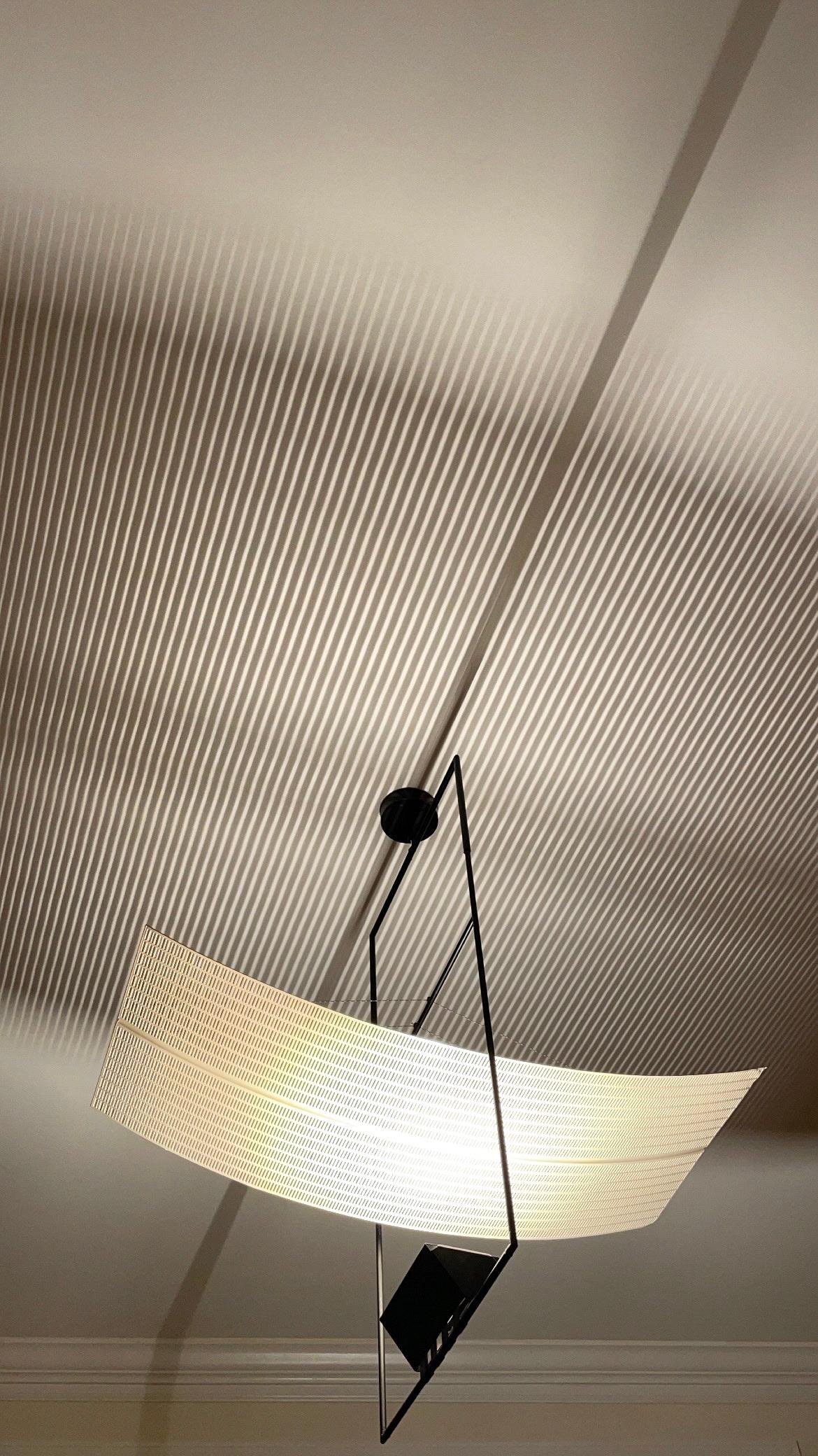 This suspension, model Zefiro, was designed by the Swiss designer Mario Botta in 1988 and then produced by Artemide. It is composed of a tubular structure in black lacquered metal on which rests a white reflector in curved perforated metal.

This