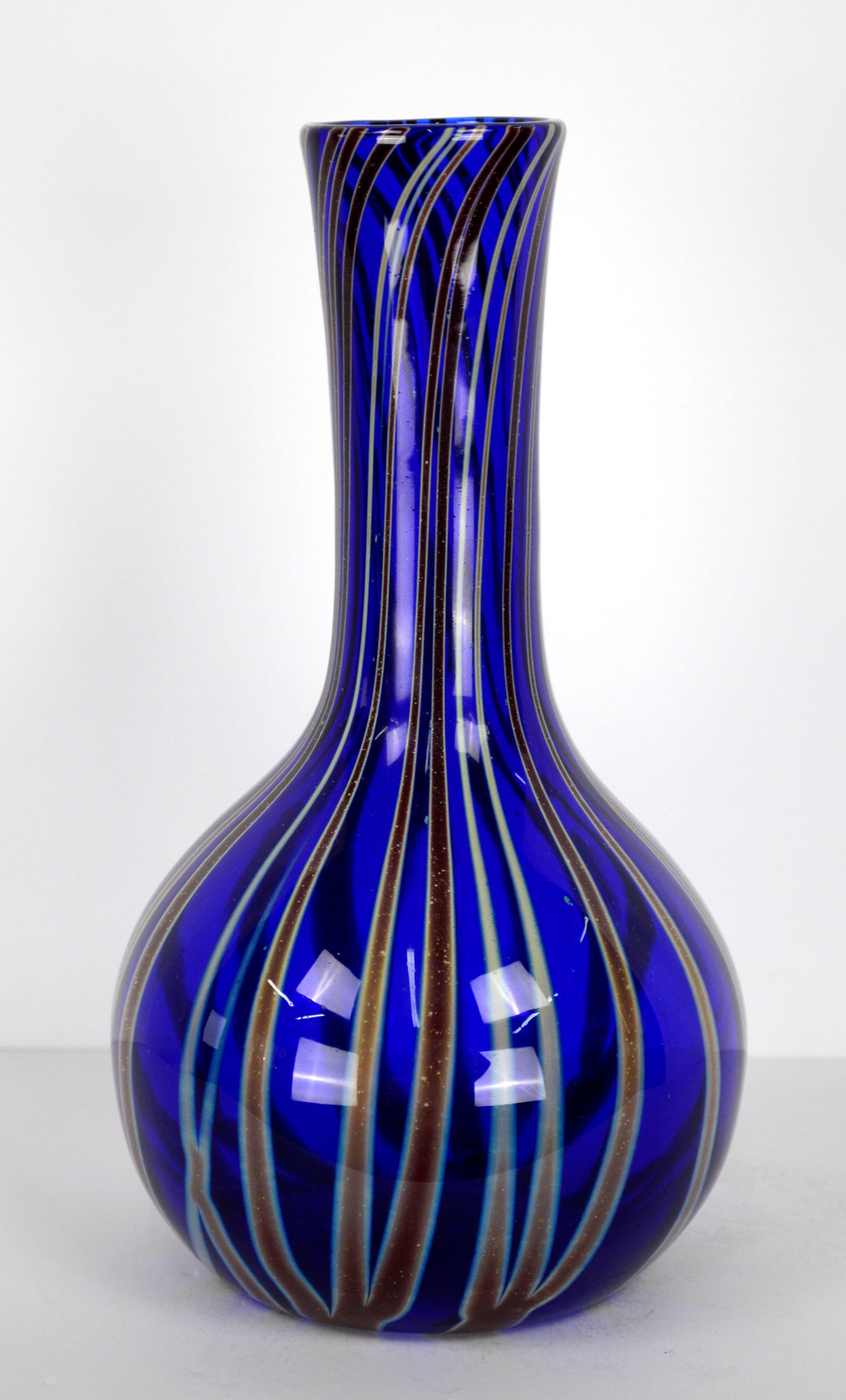 Beautiful modern blown glass vase, in bold cobalt blue with with dynamic vertical stripes in browns and earth-tones and light speckling pattern throughout, by Jim McKeever of well-known studio Zellique Art Glass (American, 20th Century), 1989. This