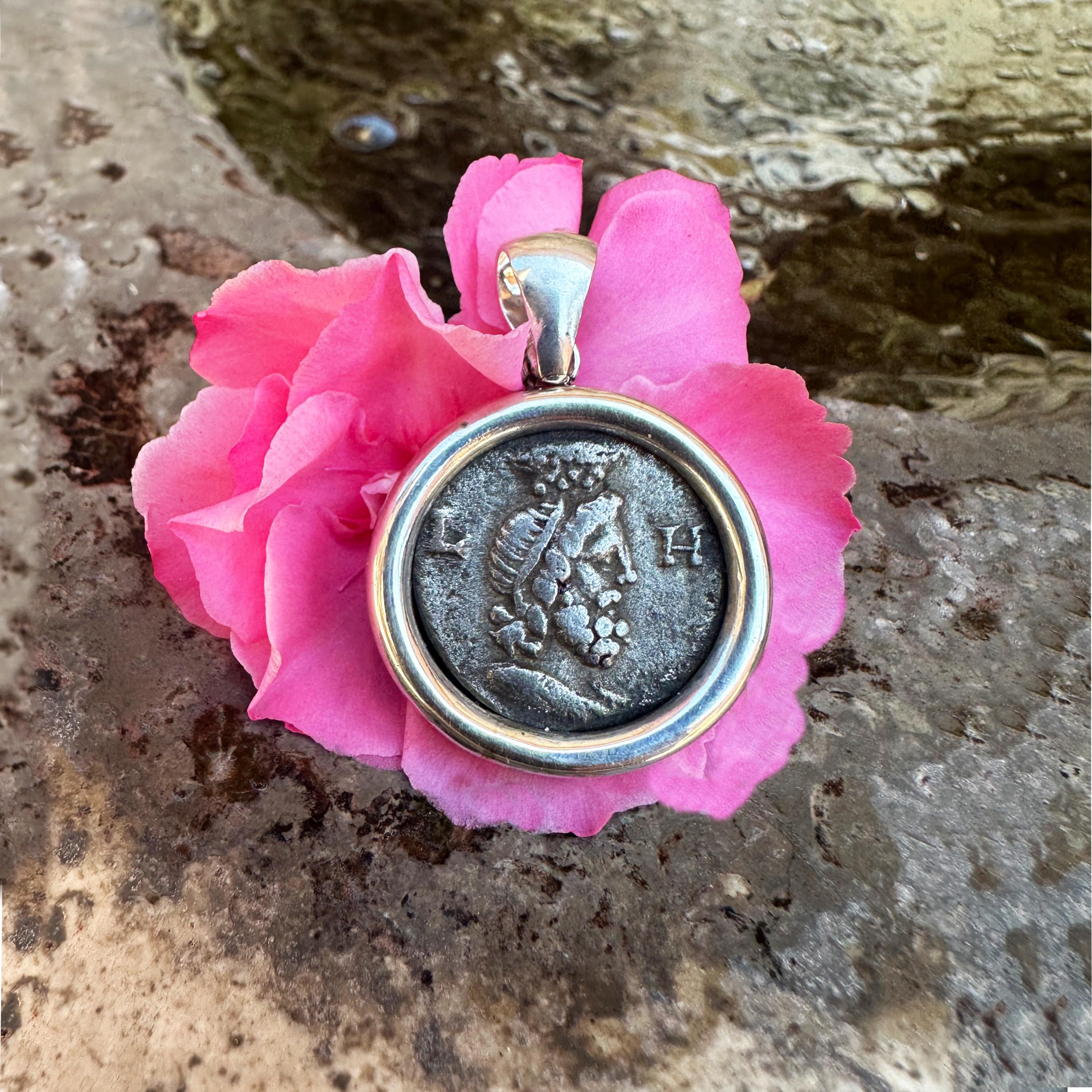 This silver pendant features an authentic Roman silver coin called a Victoriatus, dating back to the 3rd century BC. It showcases Jupiter's head adorned with a laurel wreath on one side and emperor Antoninus Pius on the rear. 

Jupiter, originally