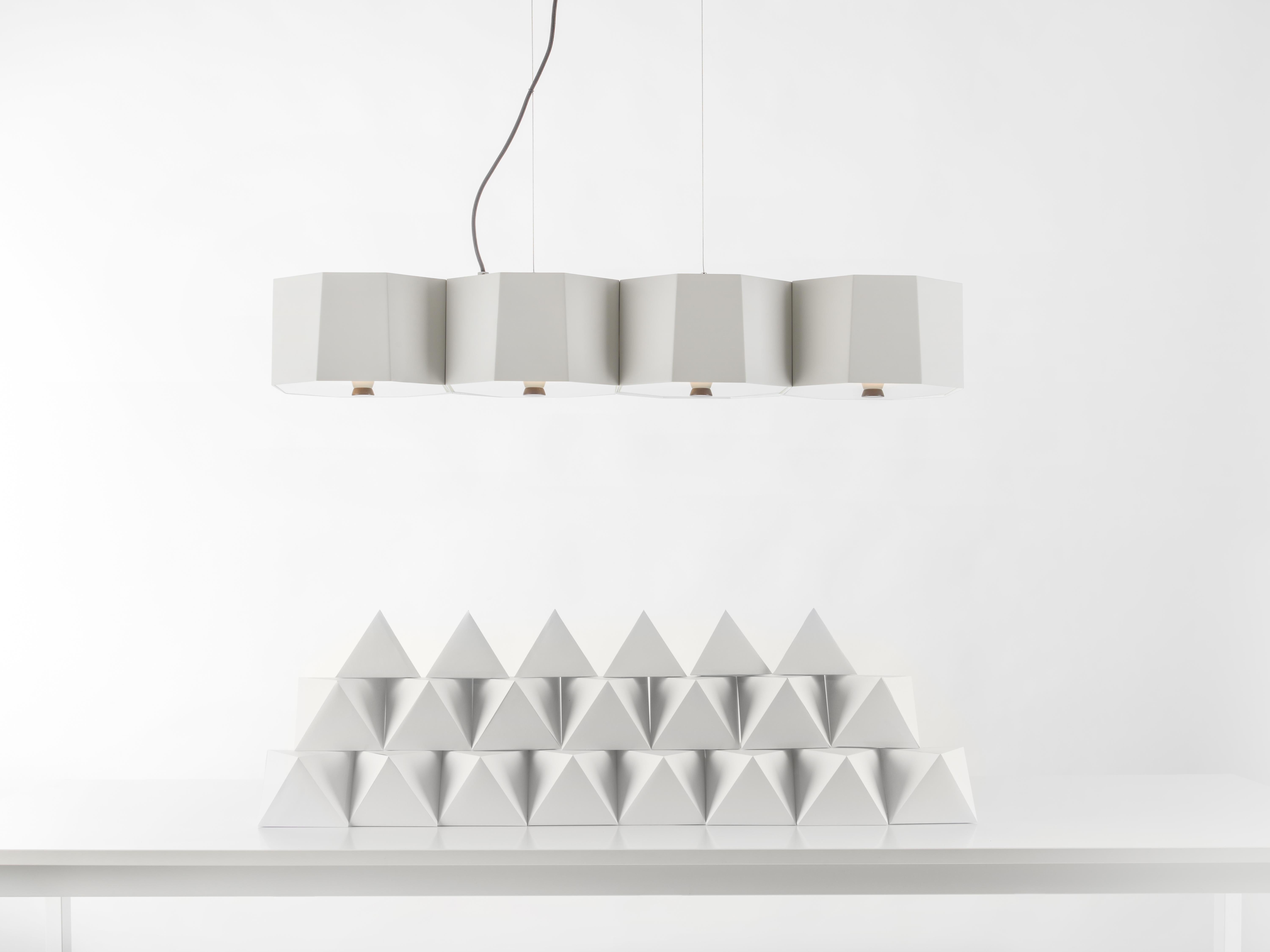 Zhe Pendant 4 is inspired by a wood from the Orient that is hard as rock. The metal lampshade is meticulously and deliberately hand welded together to resemble a cluster or rocks. Look closely and notice how each metal plate is a bit asymmetrical
