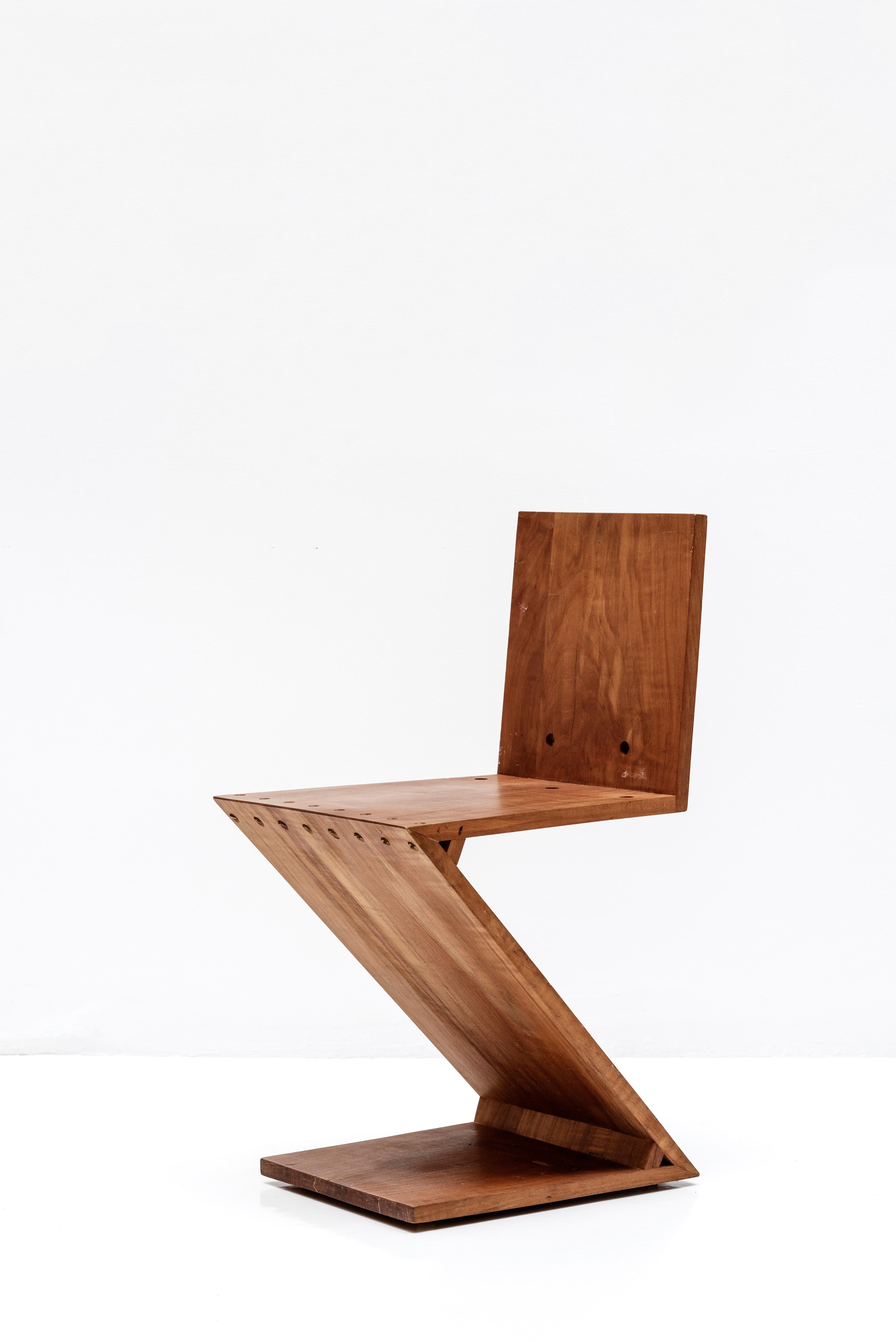 Zickzack-Stuhl von Gerrit Rietveld. Es ist ein minimalistisches Design ohne Beine, das aus 4 flachen Holzplatten besteht, die in einer Z-Form zusammengefügt sind. 
Hergestellt aus Ulme und Messing. 
Niederlande, um 1960. 
(1934 von Gerrit