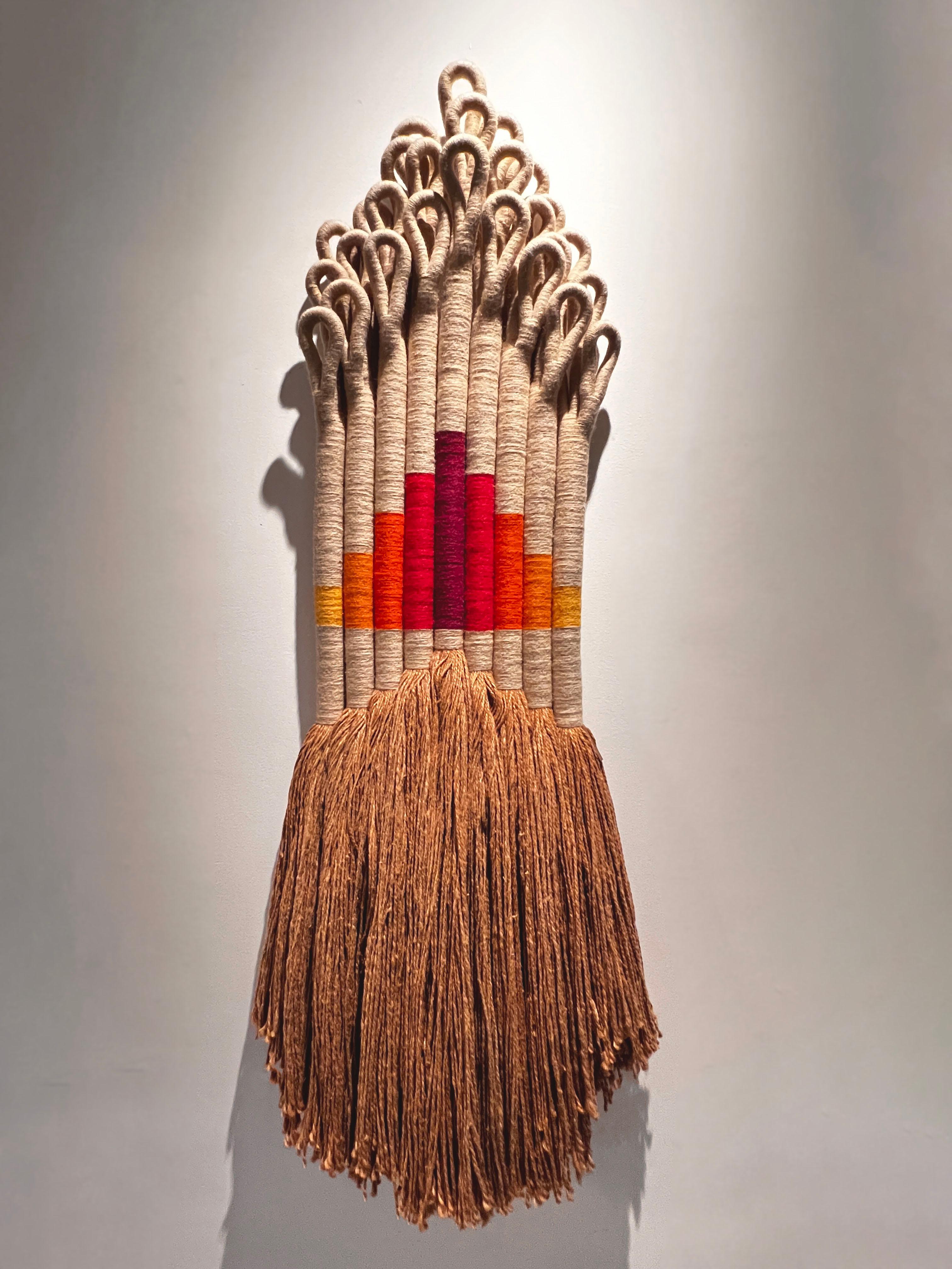 Textile installation by fiber artist Jane Knight titled 'Ziggurat'. This work is comprised of 9 vertical elements with multiple loops at the top. It is signed with an embossed copper plaque. Each element consists of hundreds of raw strands of jute