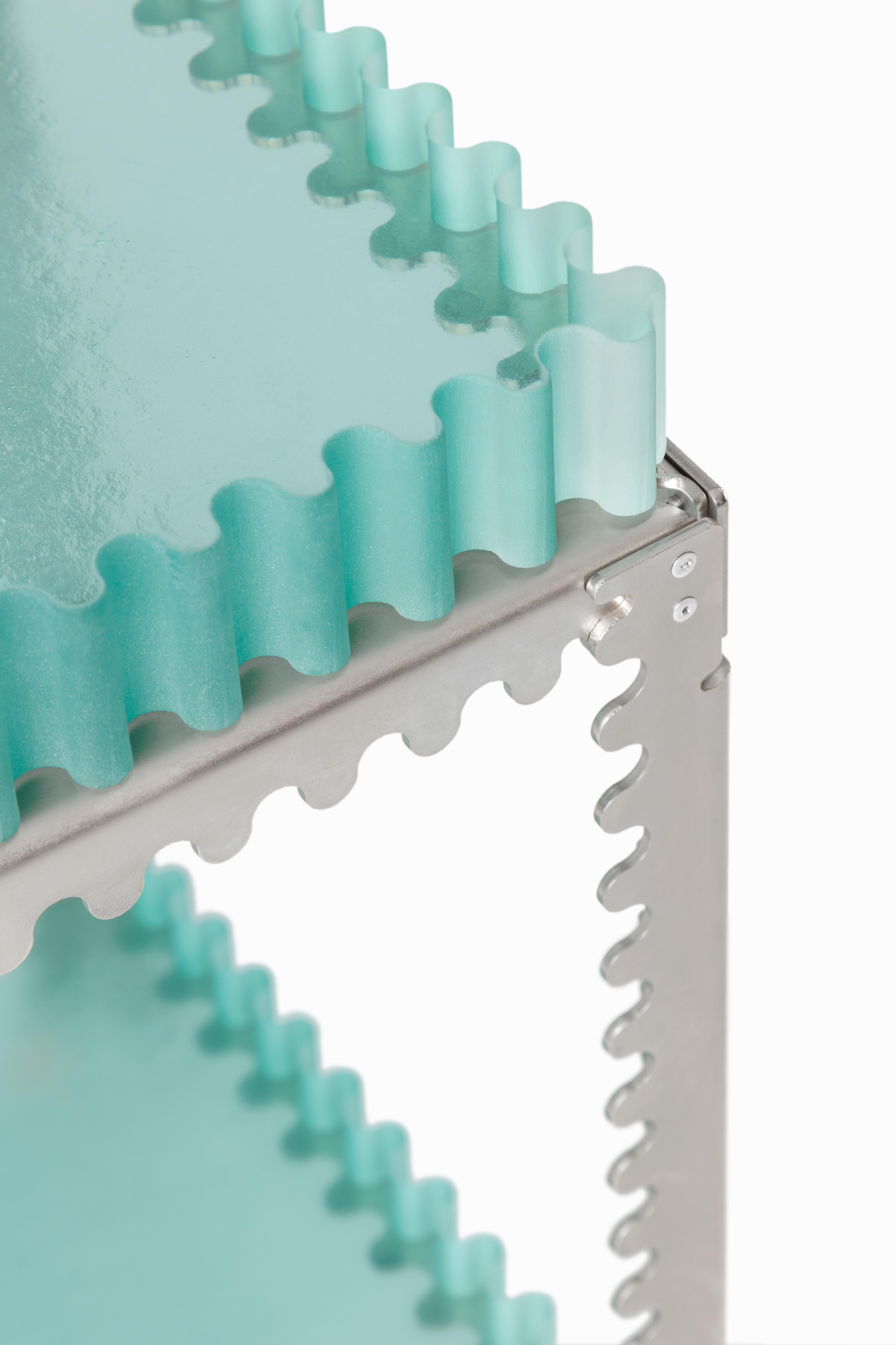 This rectangular table features two stacked cast-glass shelves within a steel frame. Its linear silhouette emphasizes modularity and verticality, creating a design that functions as side table, pedestal, or standalone object—a study in
repetition