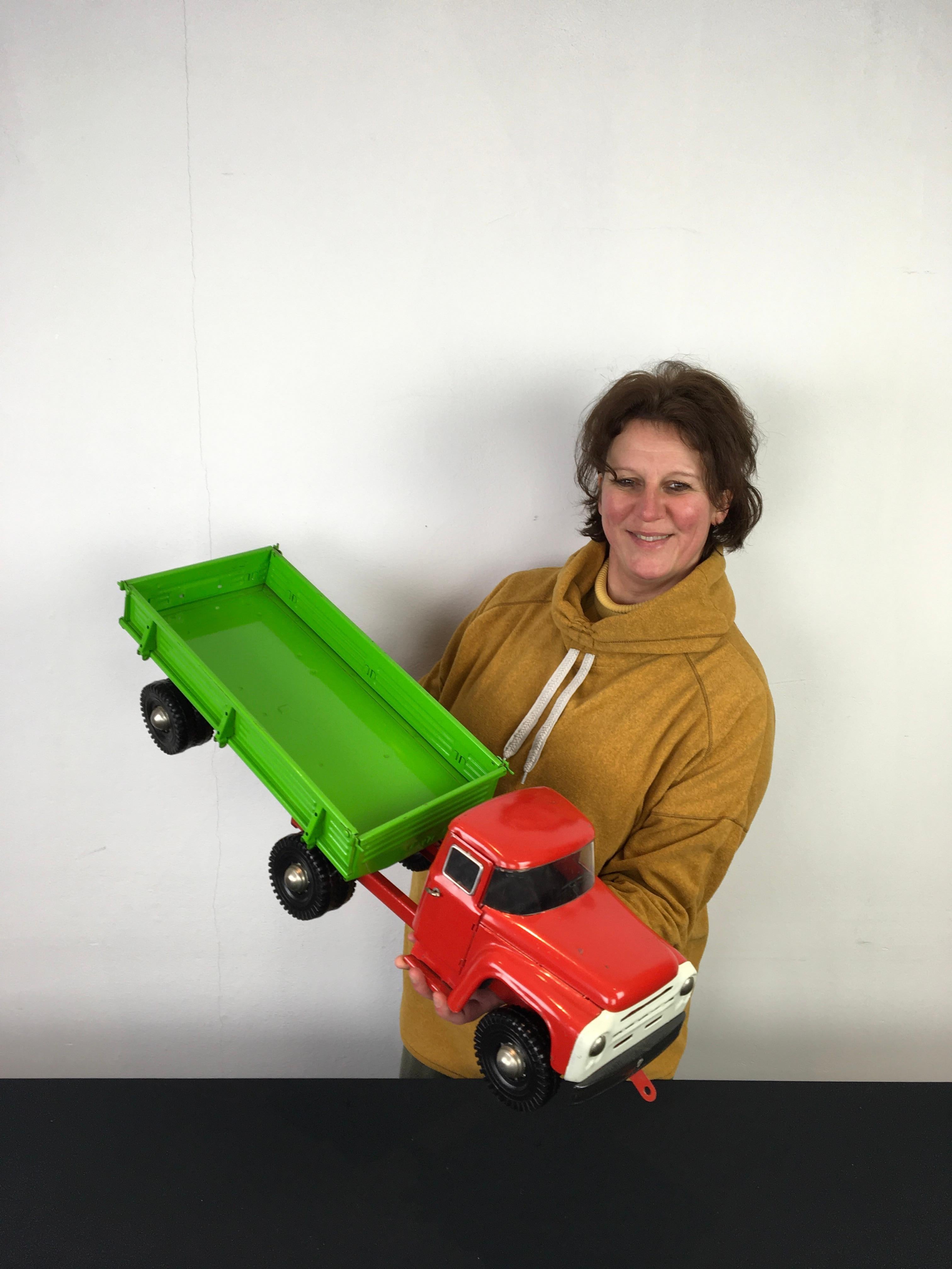 Large Zil semi-trailer truck toy. 
A large vintage metal truck toy with a red cabin and a bright green trailer. The color and painting is still original. Made in Russia in the 1980s, in 1983 which is given on the license plate at the back. 3 flaps