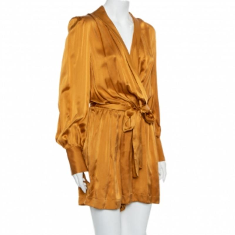 An exquisite fusion of chic & sophisticated style, this Zimmerman ensemble will lend an edge to your personality. Cut from luxurious satin, it carries a lovely gold hue, features a belt around the waistline, and a faux wrap-around style. The V