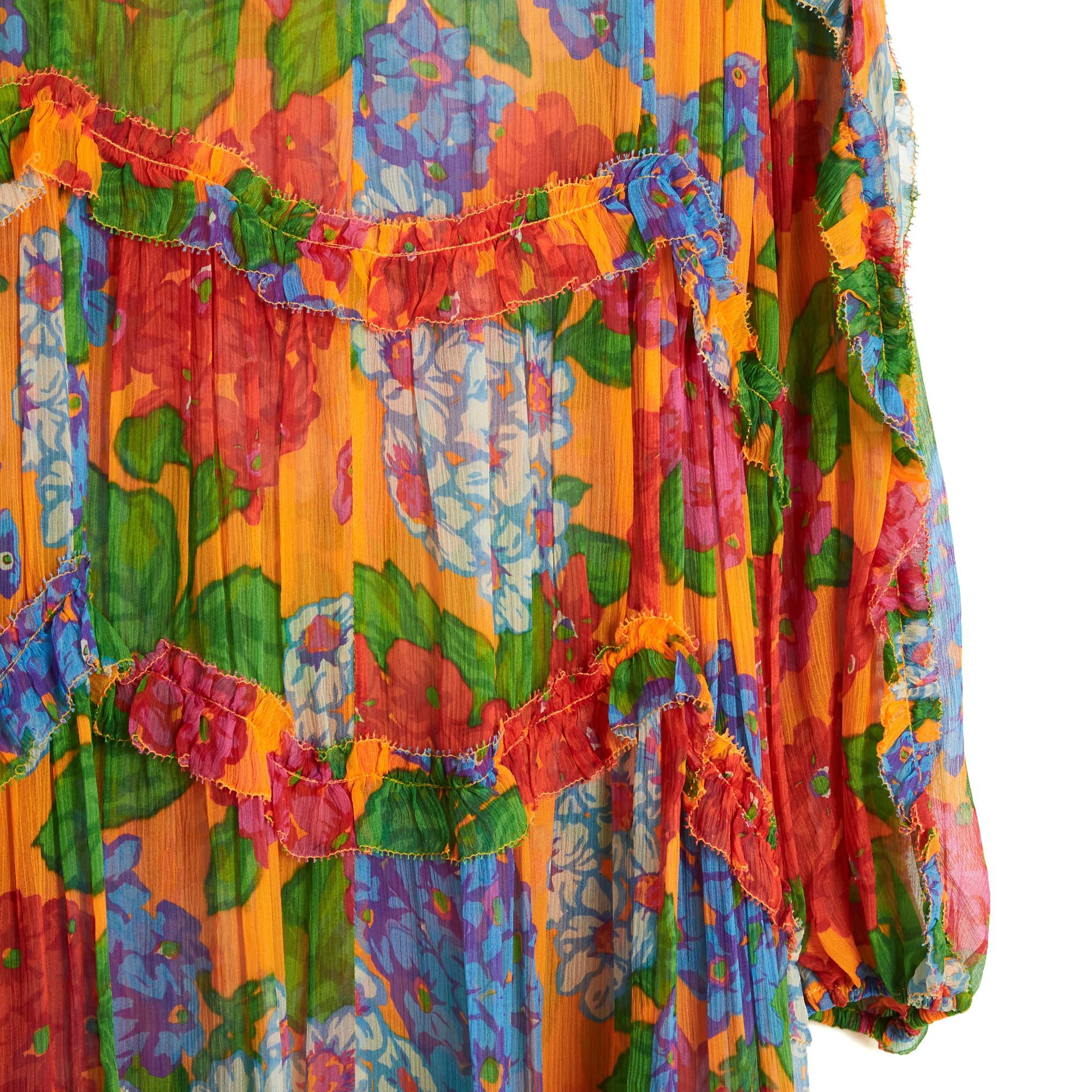 Robe longue et oversize Zimmermann en mousseline de soie à motif floral multicolore, avec un petit volant sur l'ensemble de la robe, col rond fendu à resserrer par 2 liens perlés, manches longues raglan resserrées par un élastique, jupe asymétrique