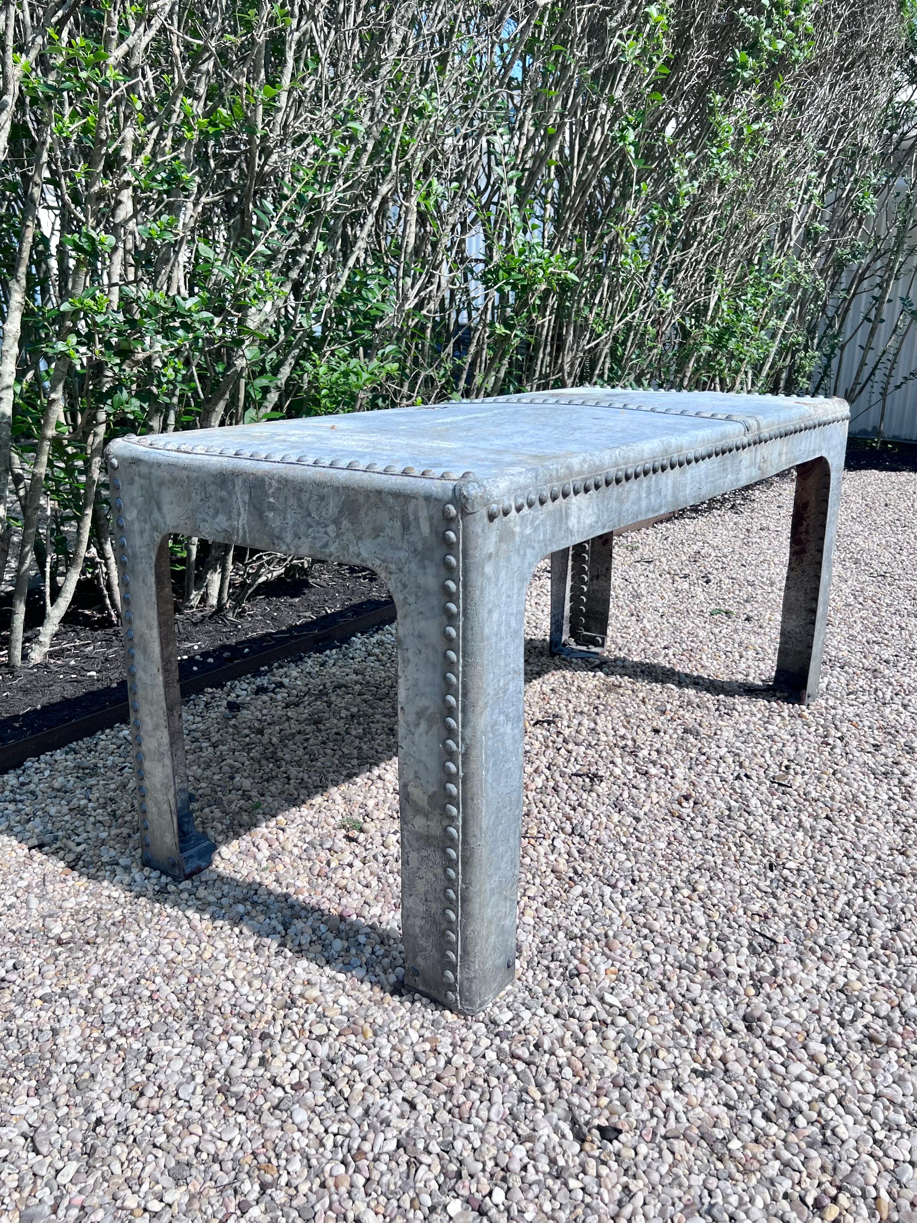 Wonderful industrial riveted metal table in solid galvanized steel/zinc. Table with metal rivets welded to the top and sides. Was most likely used in a factory or barn at some point. Incredibly hard-wearing and sturdy, this table would look