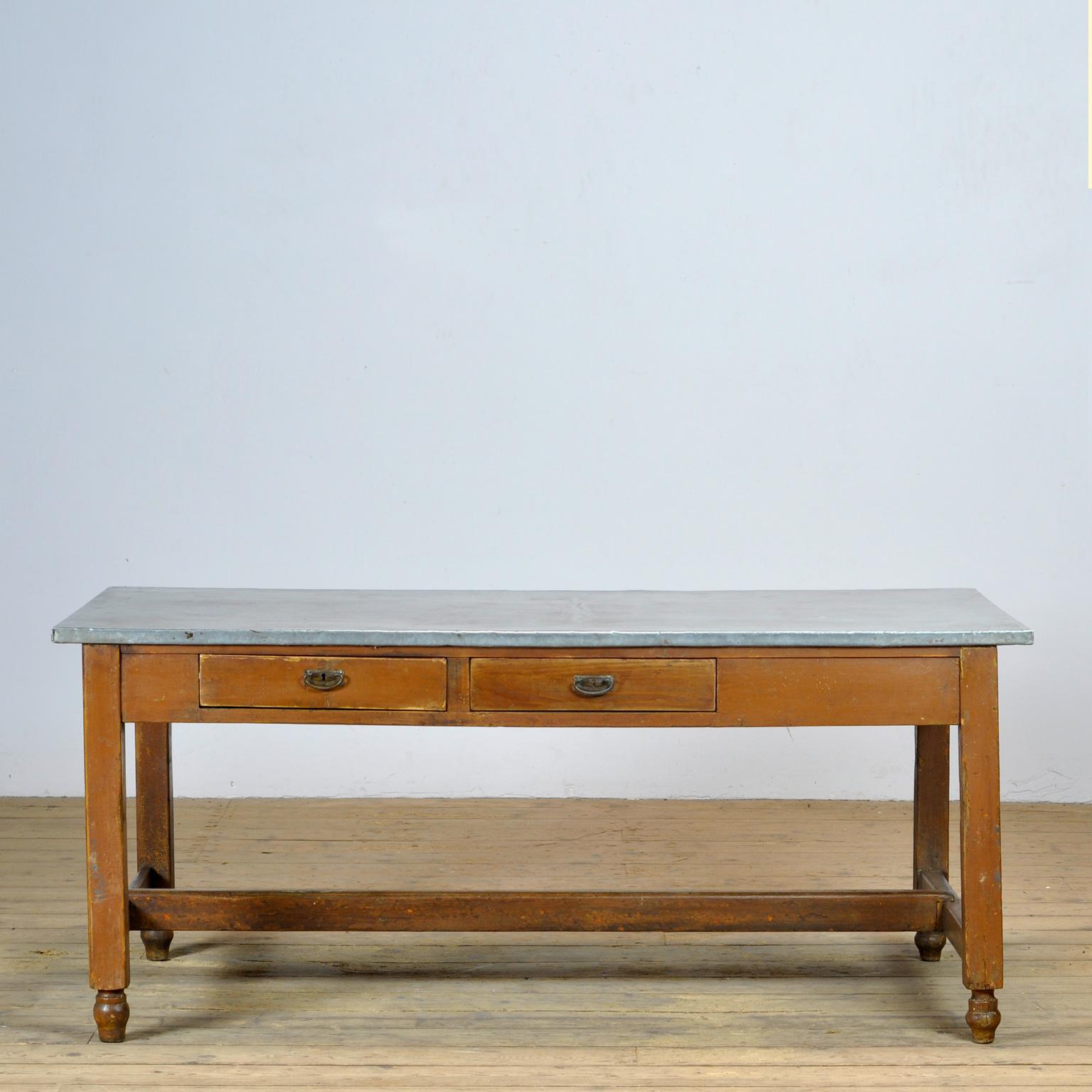 A pine work table with its original zinc top. The table has three drawers. The table was produced in France around 1930. The wood has its original naturally weathered varnish.
